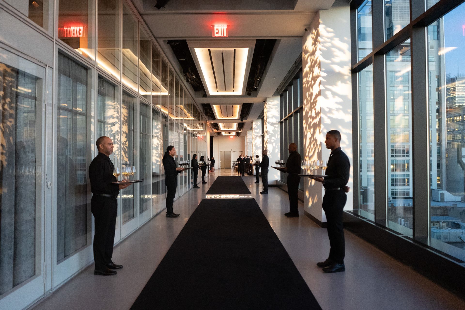 A group of people are standing in a hallway holding trays.