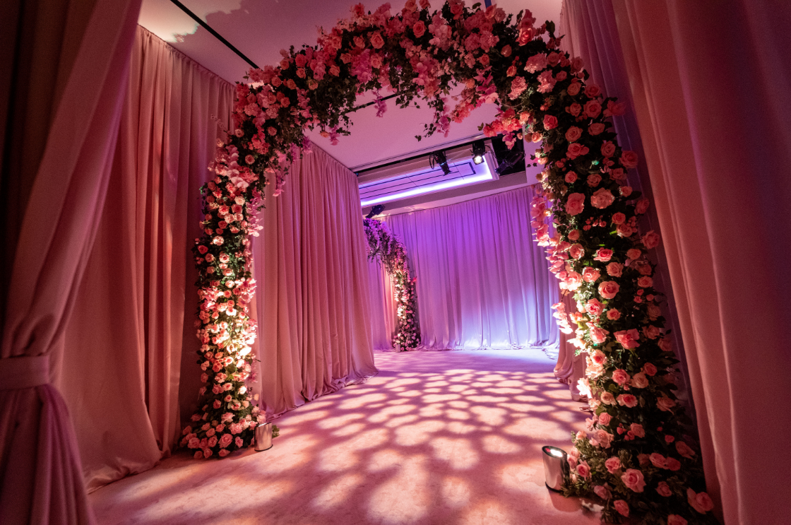a room decorated with pink curtains and flowers for a wedding .