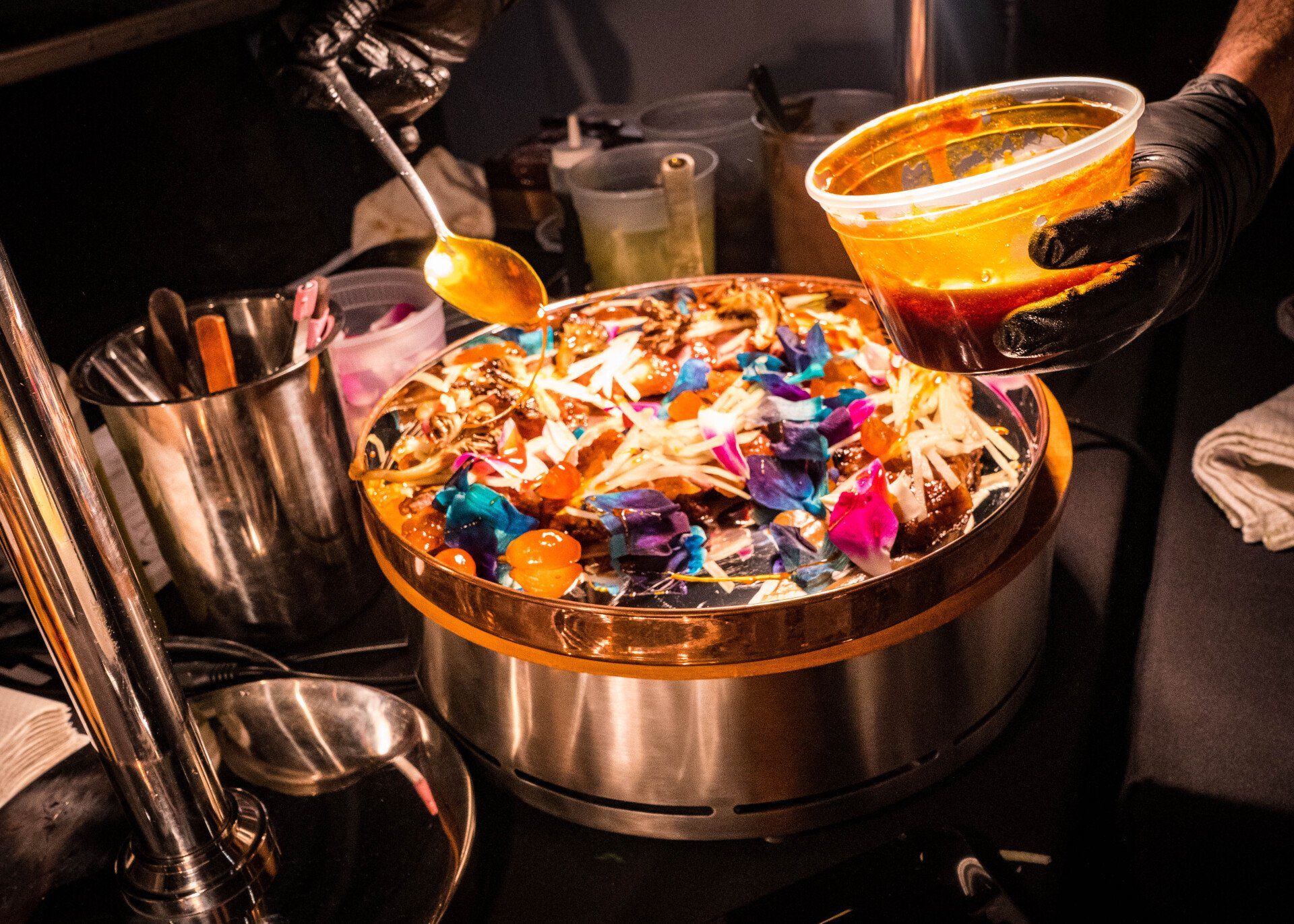 A person is pouring sauce on a pizza with a spoon.