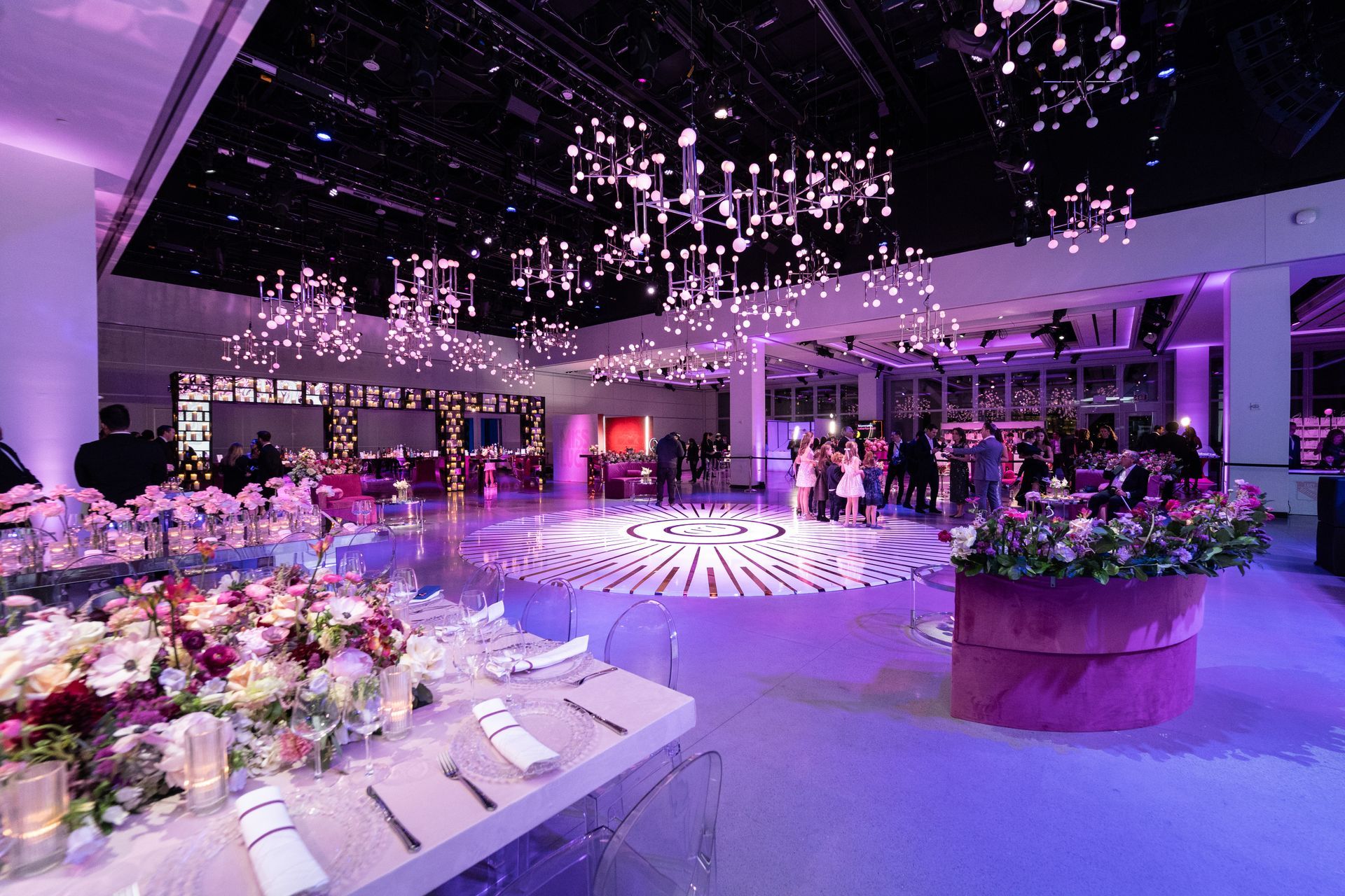 Elegant event space with round dance floor, tables set for dinner, purple lighting.