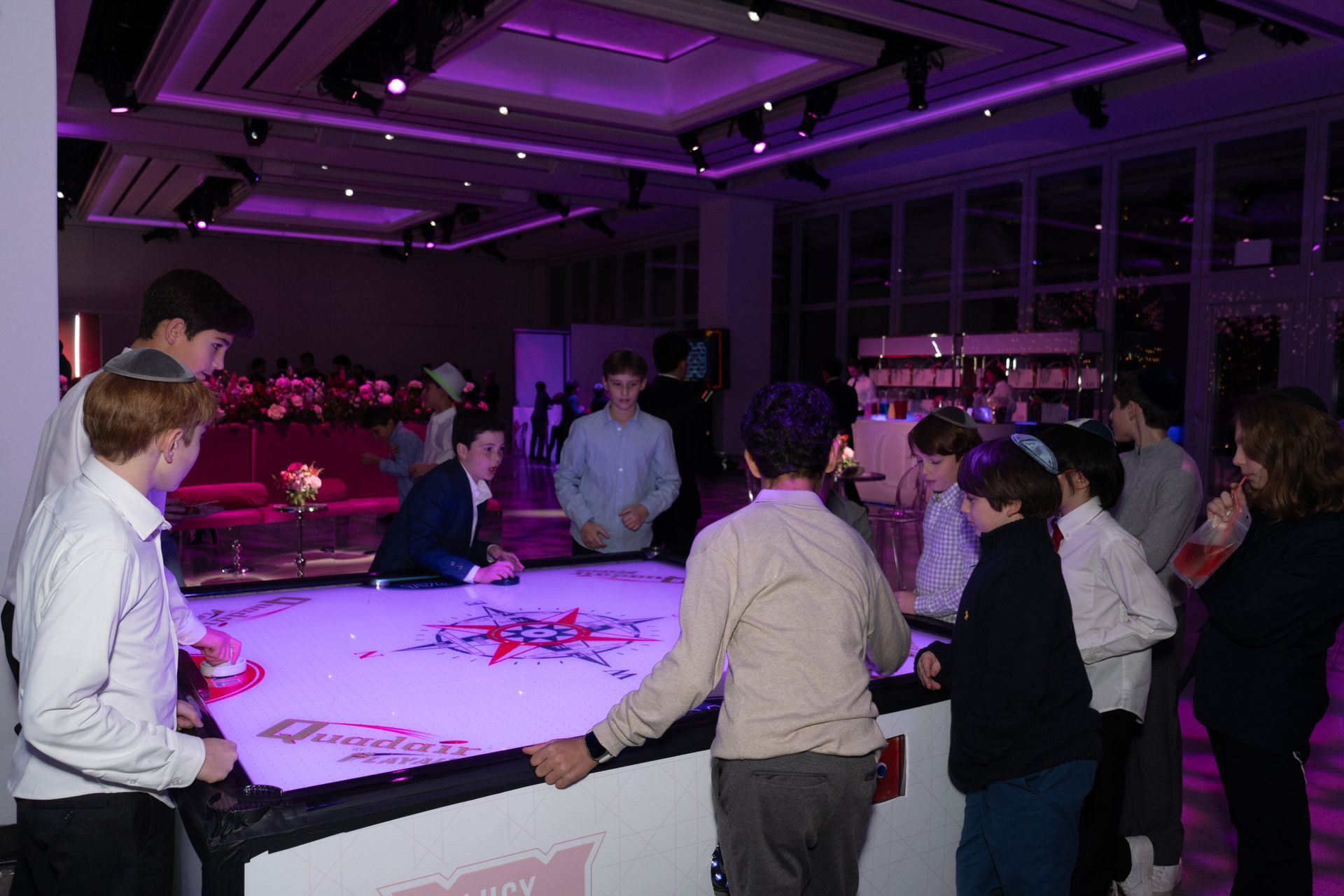 Group of young people at a party, gathered around a lit-up table.