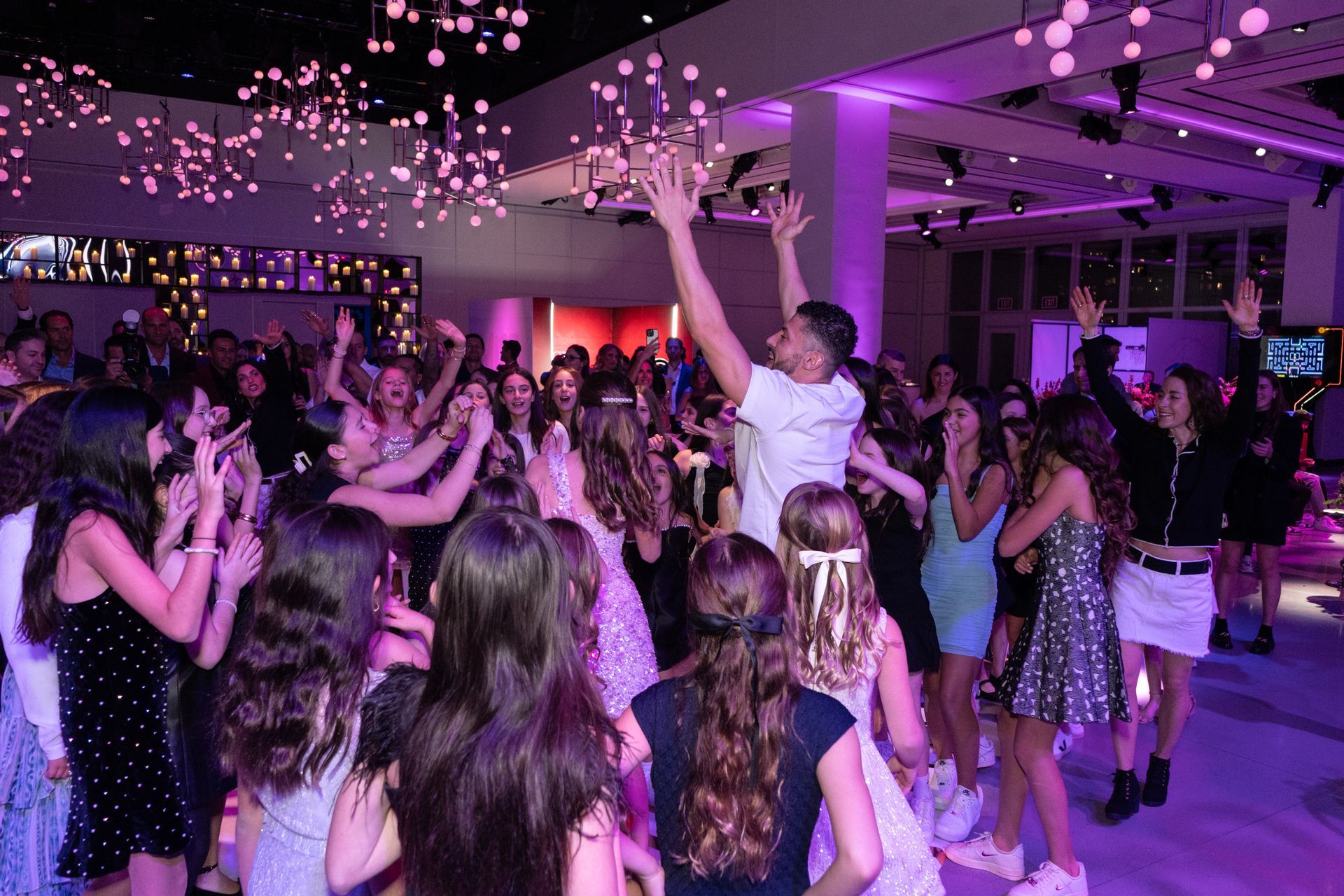 People dancing at a party with overhead lights. One person is lifted up by others, arms raised.