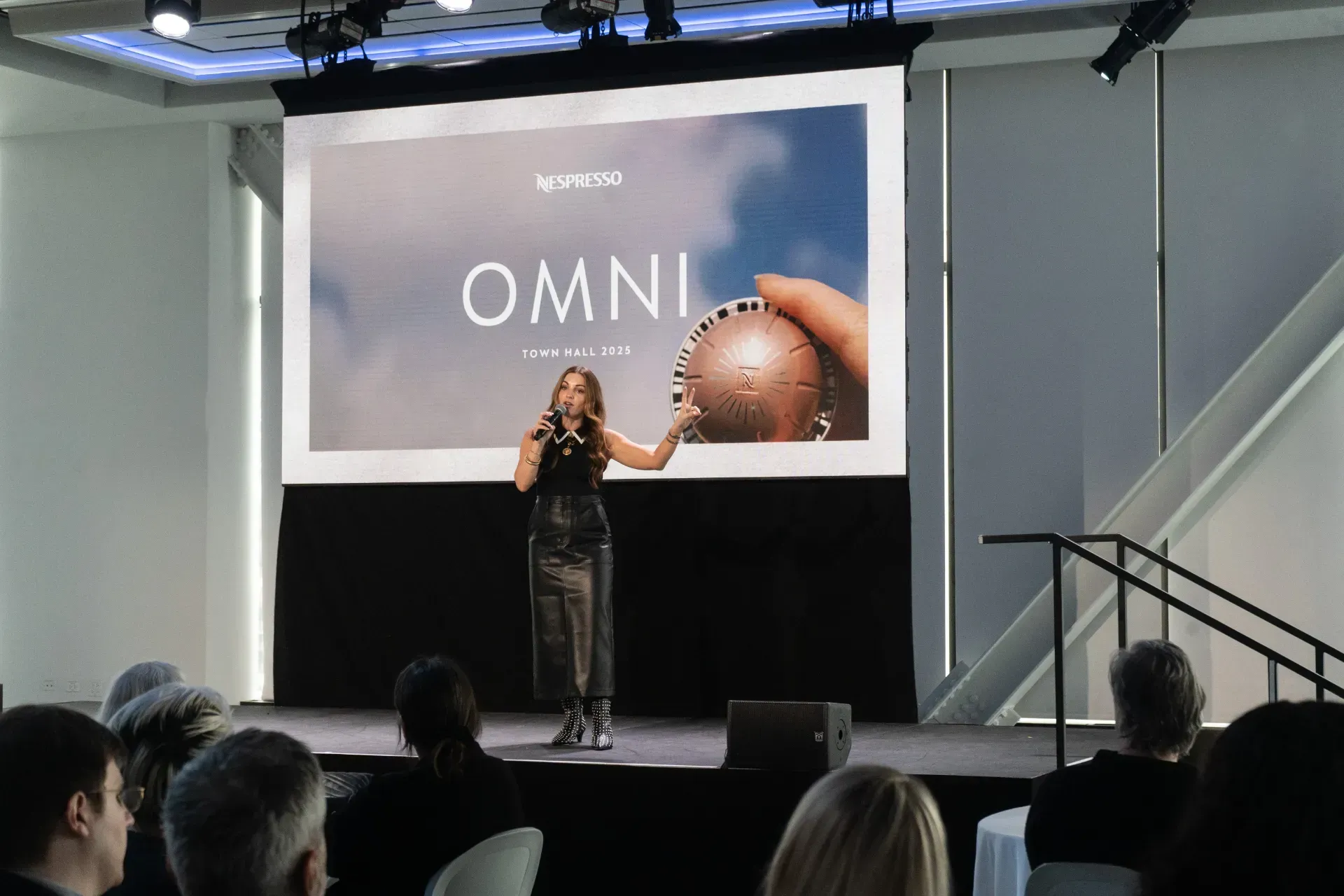 A woman is giving a presentation in front of a screen that says omni