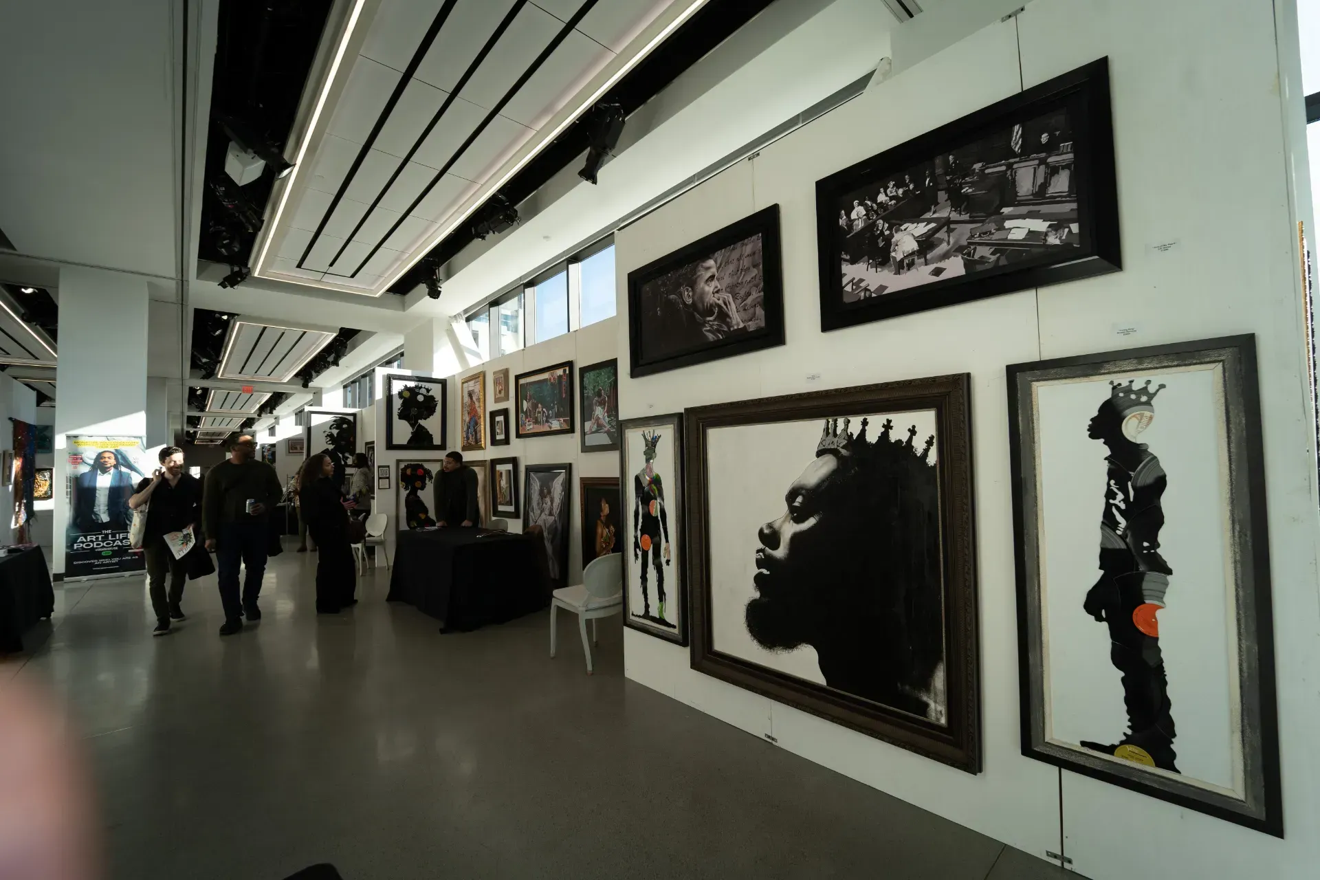 A group of people are standing in a room with a lot of pictures on the wall.