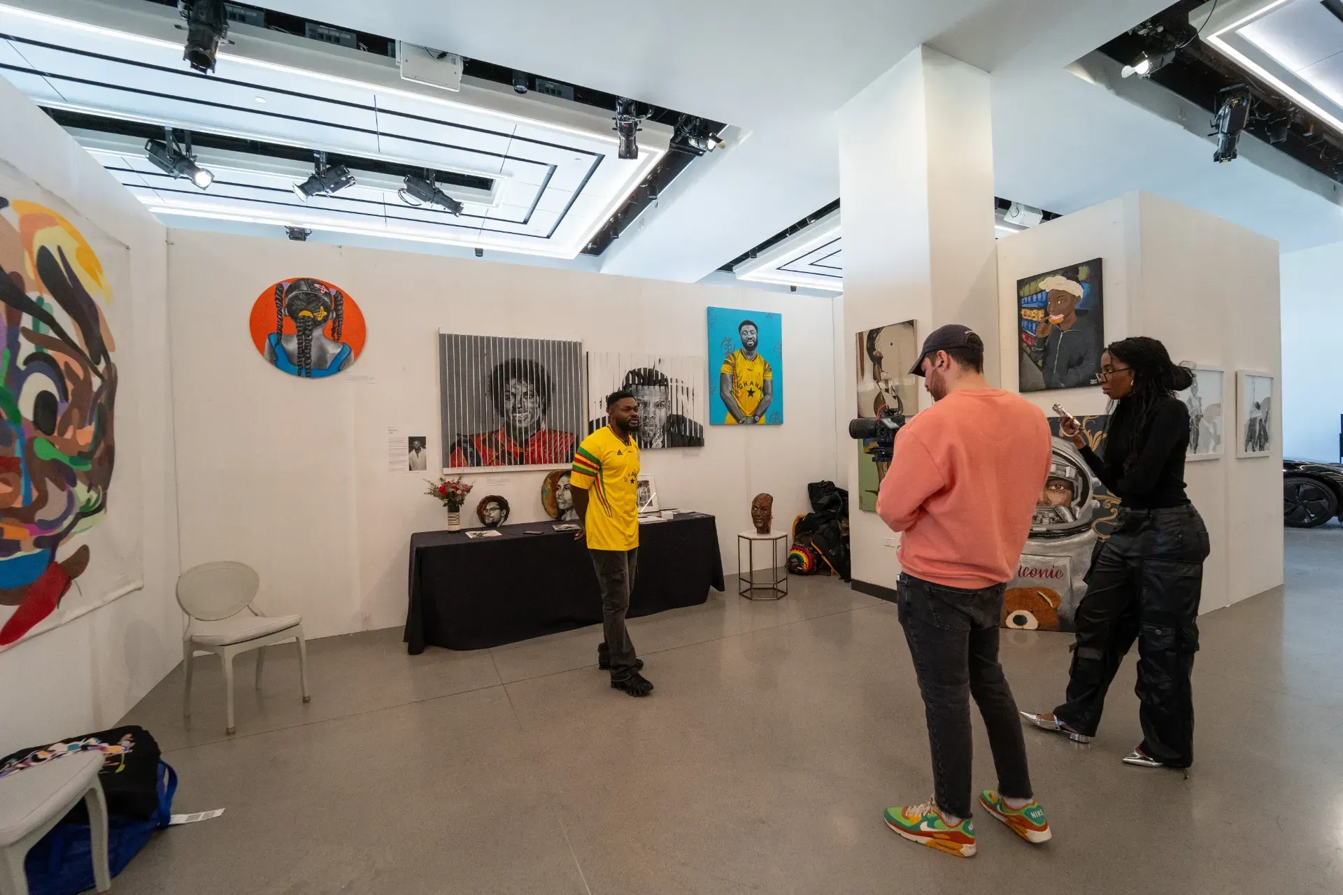A group of people are standing in a room with paintings on the walls.