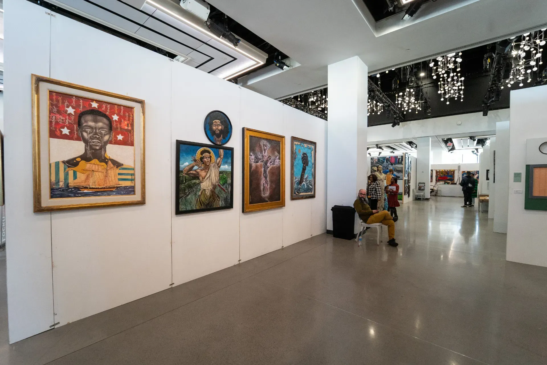 A group of people are looking at paintings in a museum.