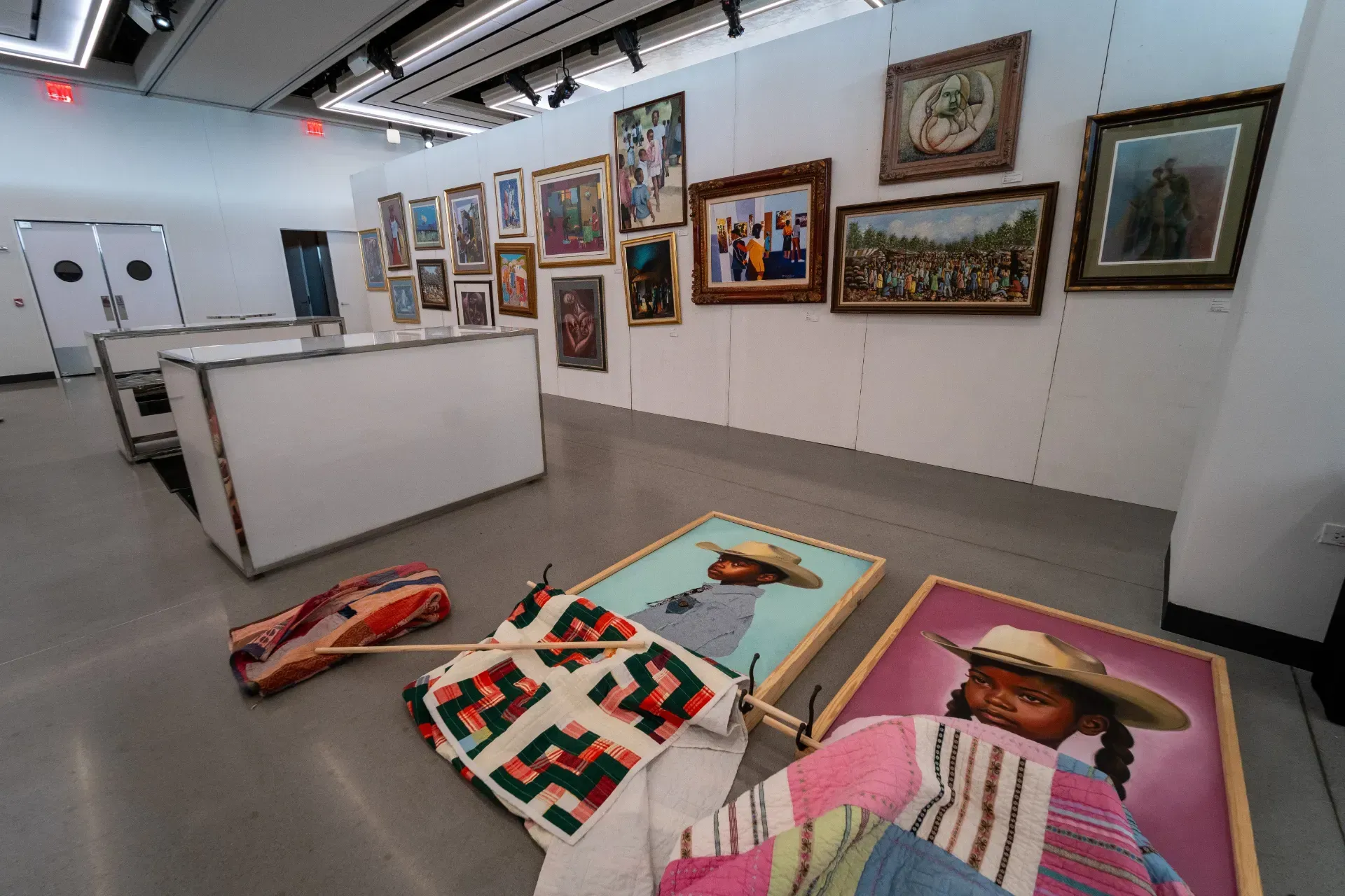 A room with a lot of paintings on the wall and on the floor.