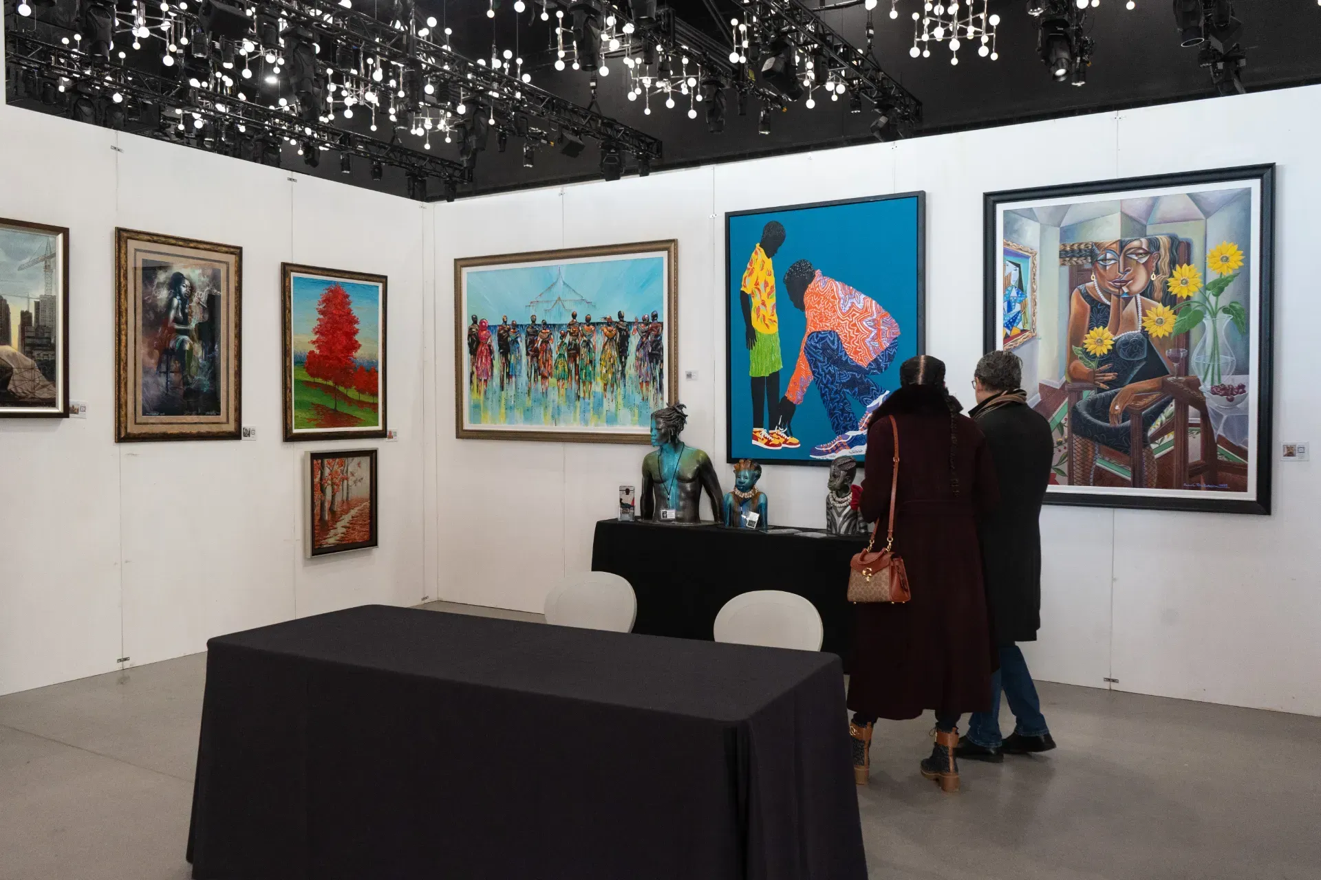 A group of people are looking at paintings in a museum.