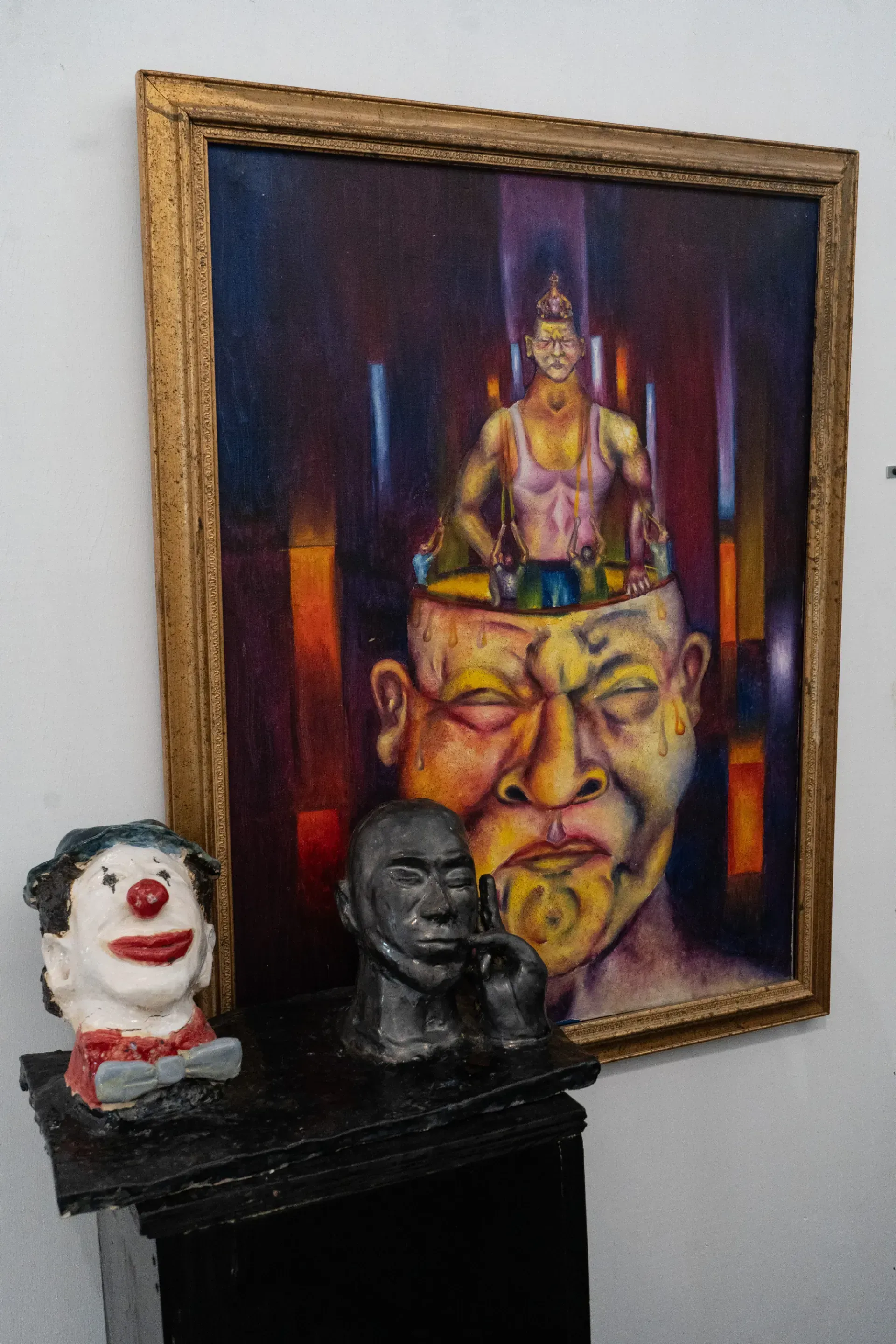 A painting of a man with a clown head in front of it