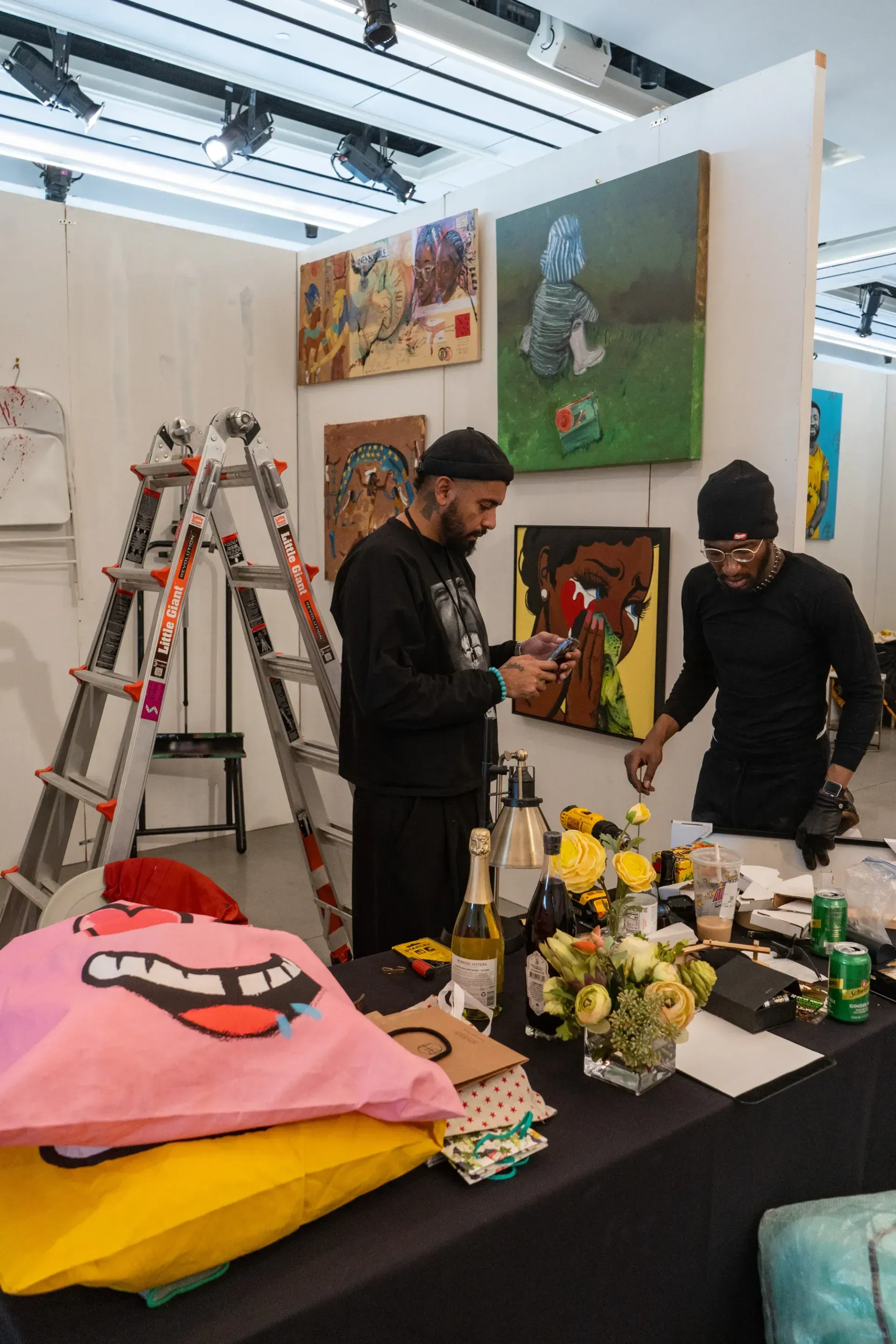 Two men are standing next to each other in a room with paintings on the wall.
