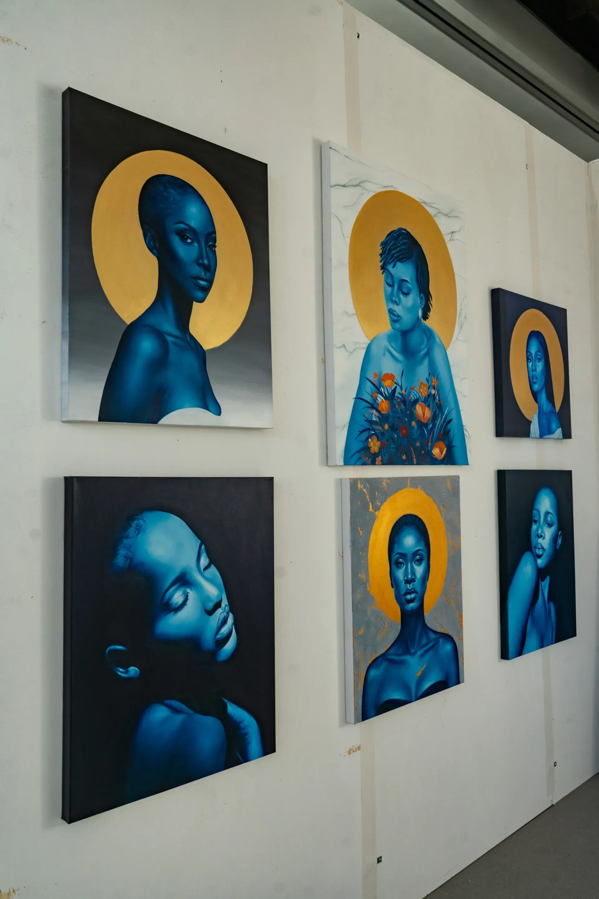 A wall with four paintings of a woman on it.