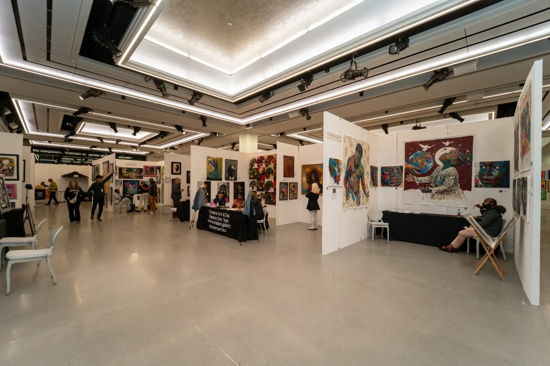 A large room filled with lots of paintings and people.