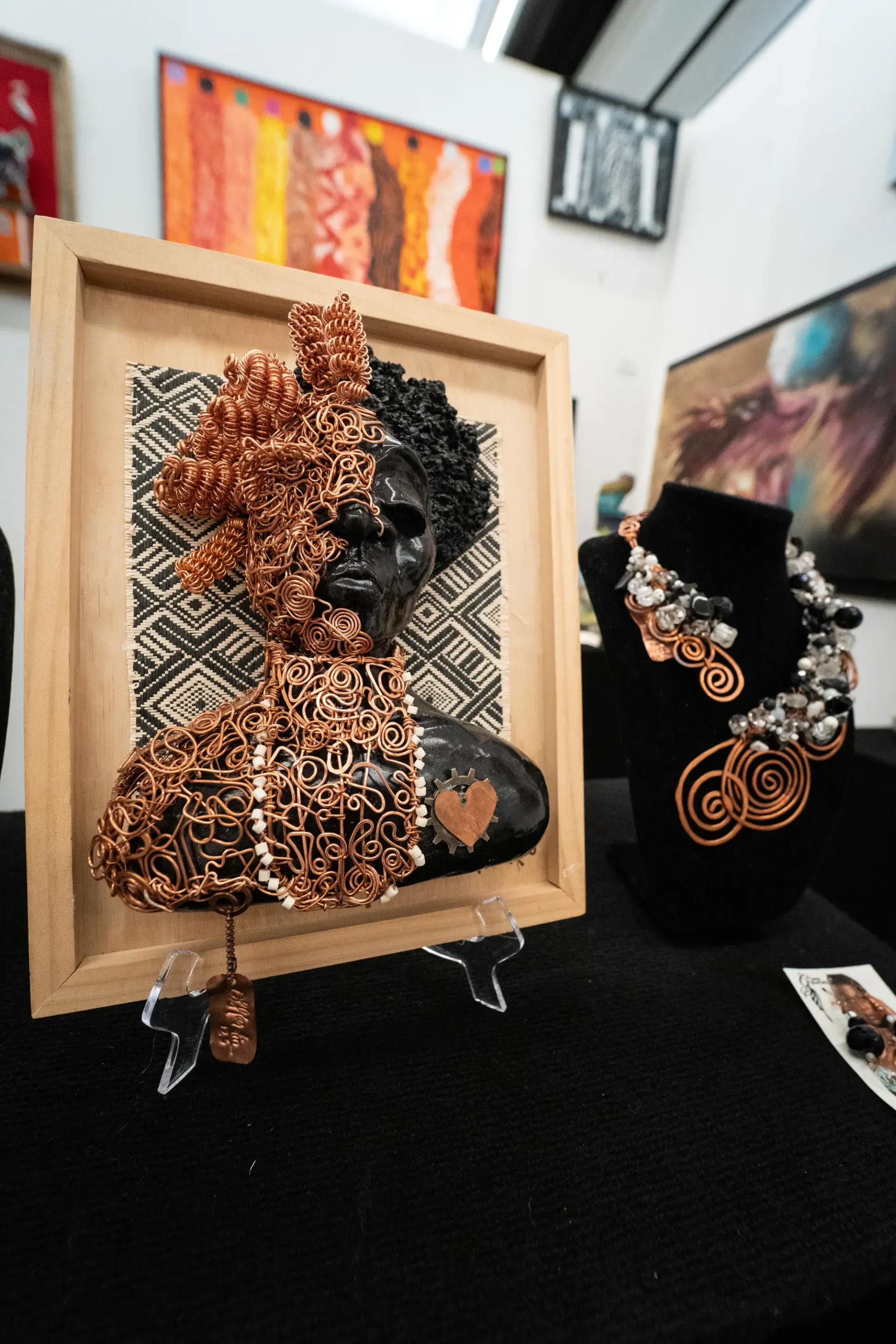 A painting of a woman 's face is on a table next to a necklace and earrings.