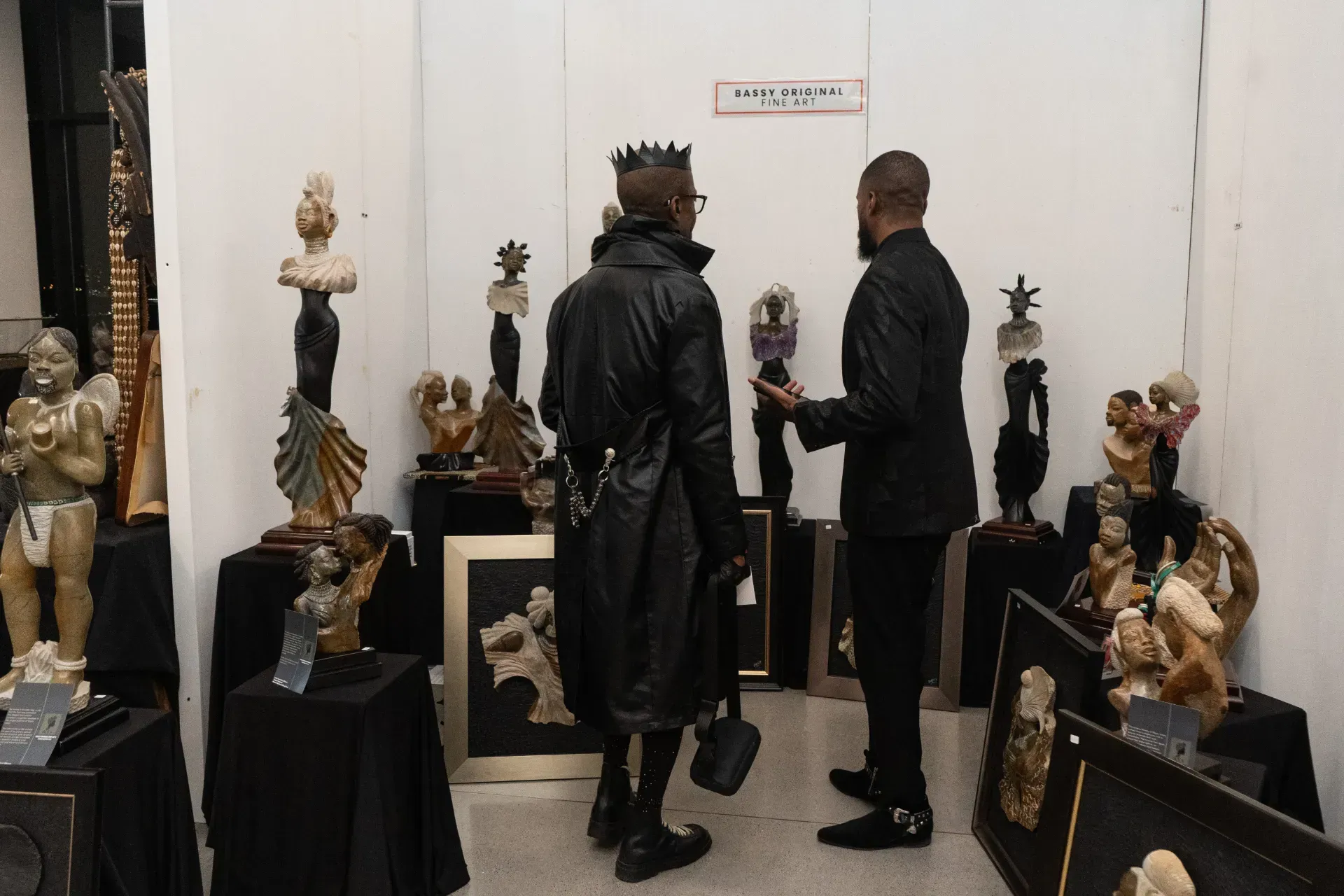 Two men are standing in a room with statues on display