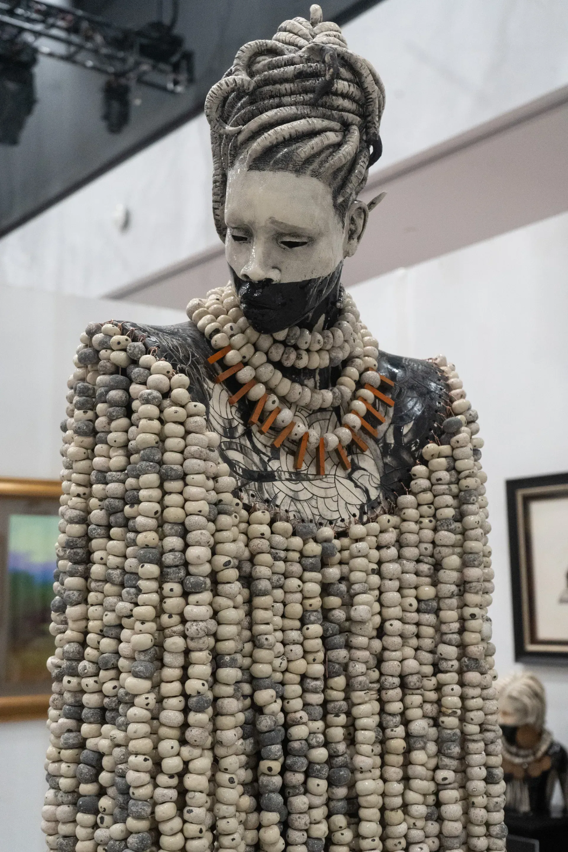A statue of a woman with dreadlocks is covered in beads.