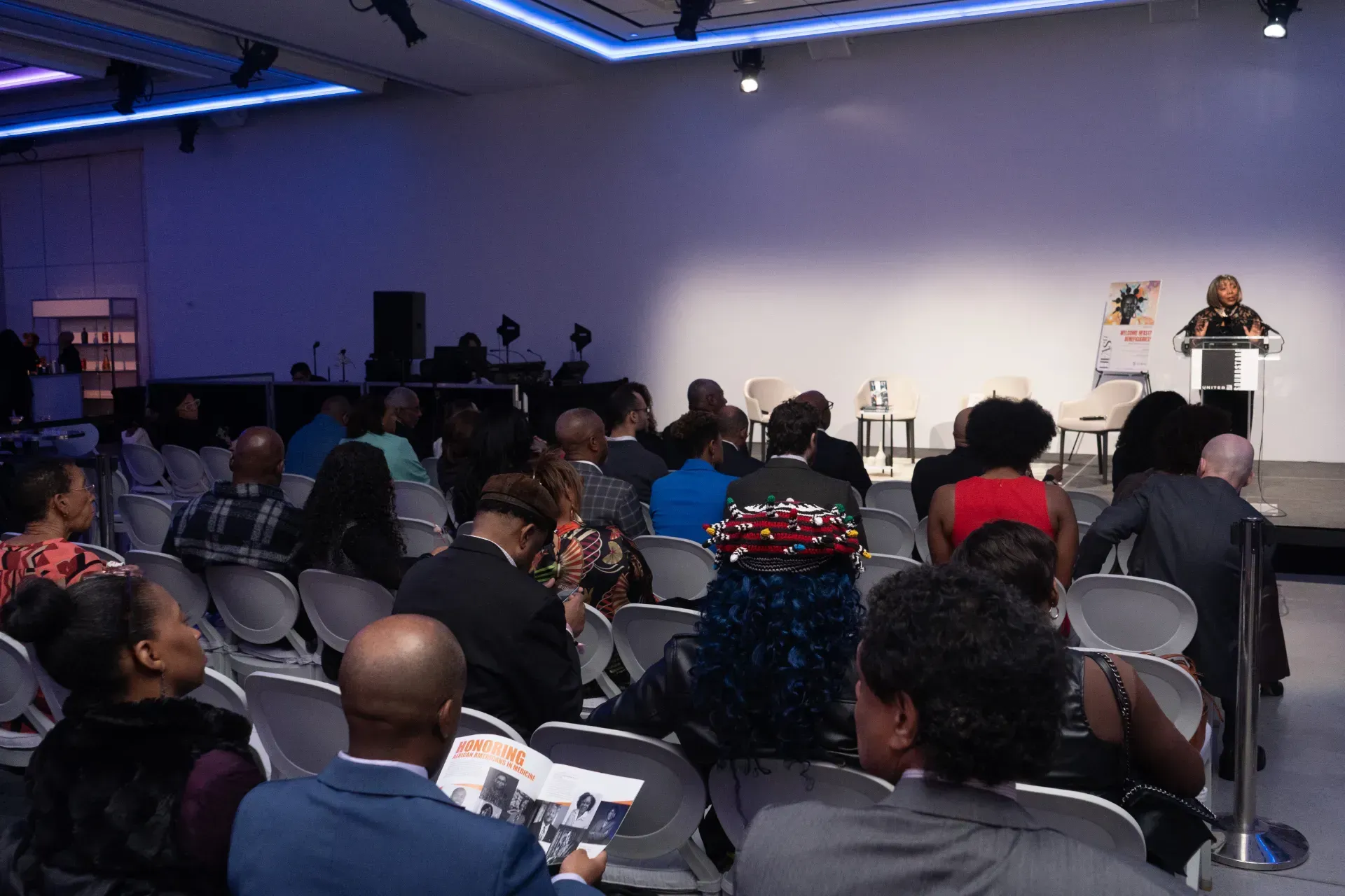 A woman is giving a speech in front of a crowd of people