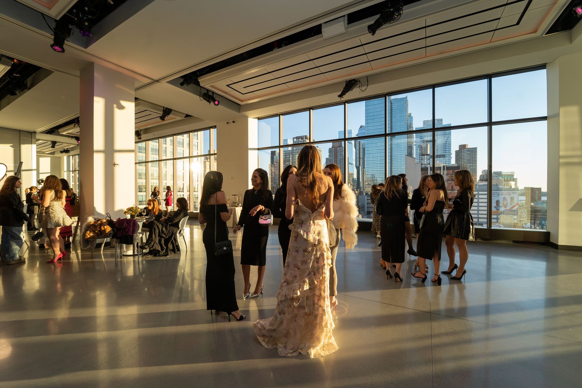 A group of women are standing in a large room with a lot of windows.