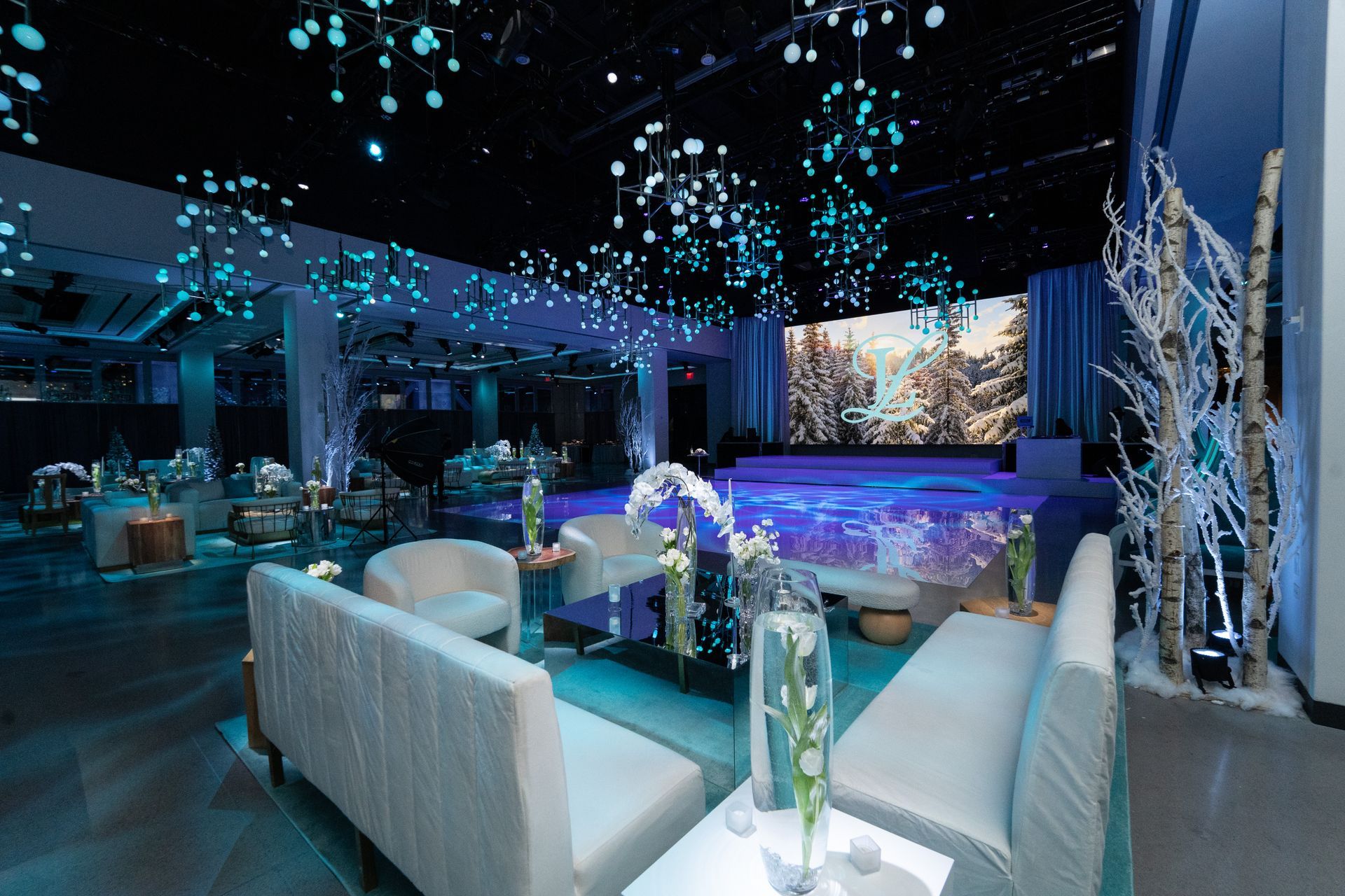 A winter wonderland-themed event space with white furniture, blue lighting, and snowflake decorations.