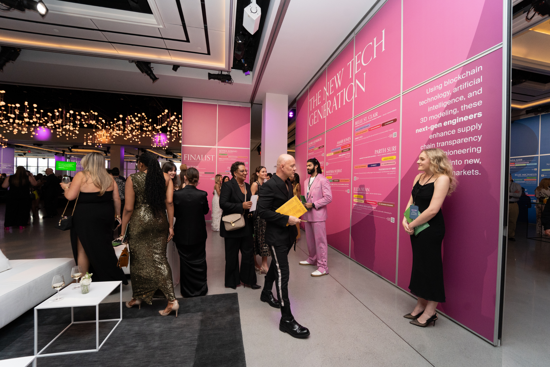 A group of people are standing in front of a pink wall.