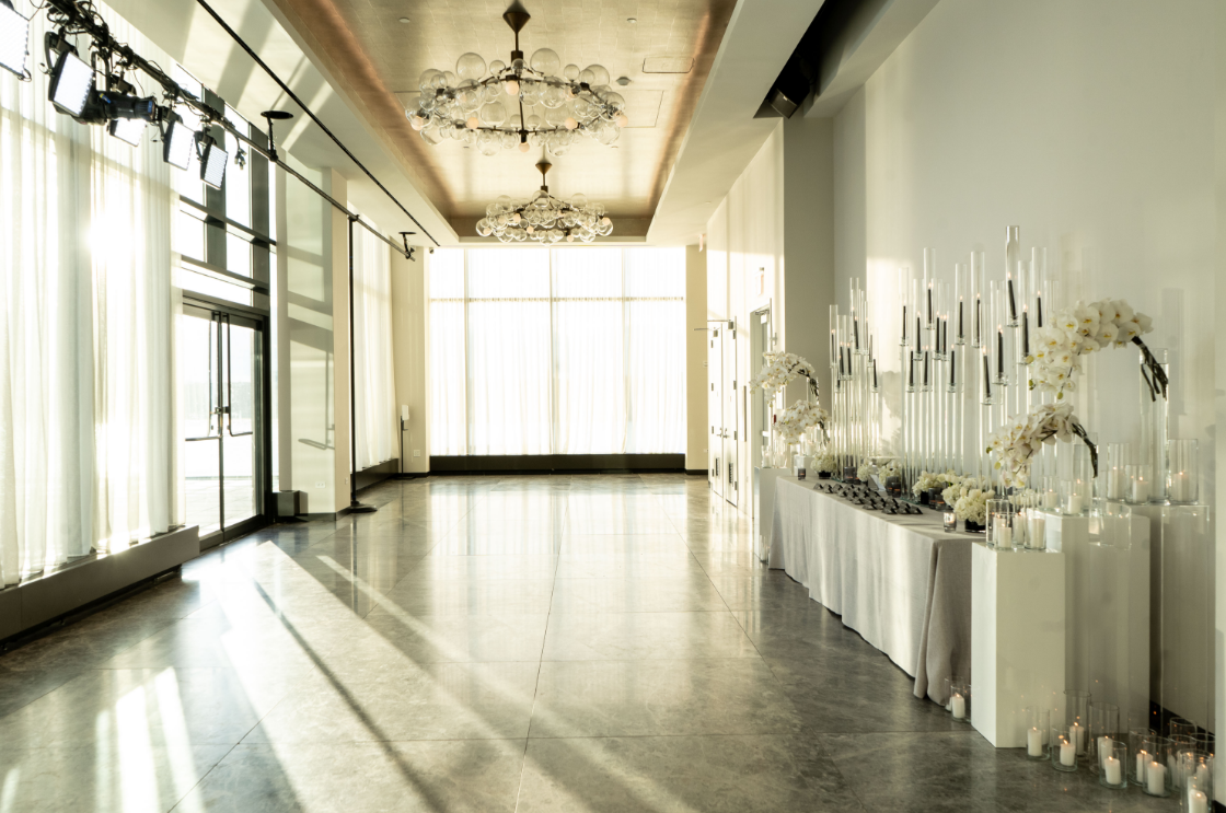 A large empty room with a lot of windows and candles on the floor.