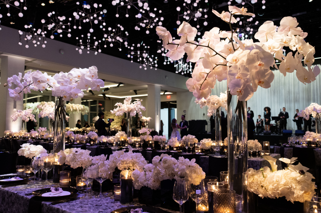 a room filled with tables and vases of flowers and candles .