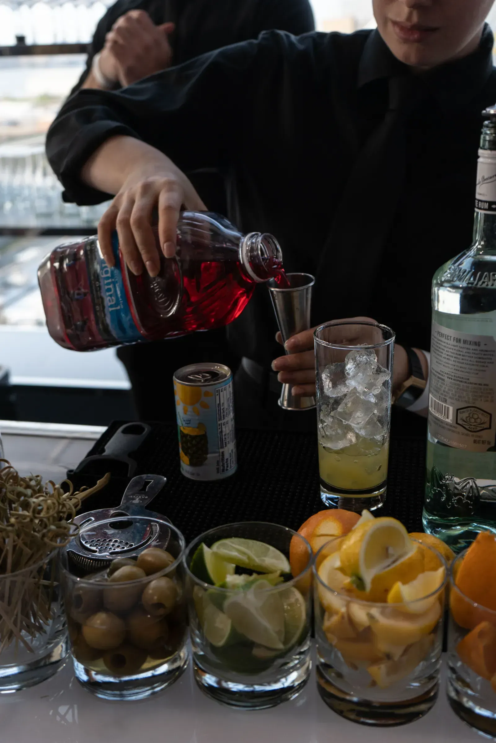 A bartender is pouring a drink into a shot glass.
