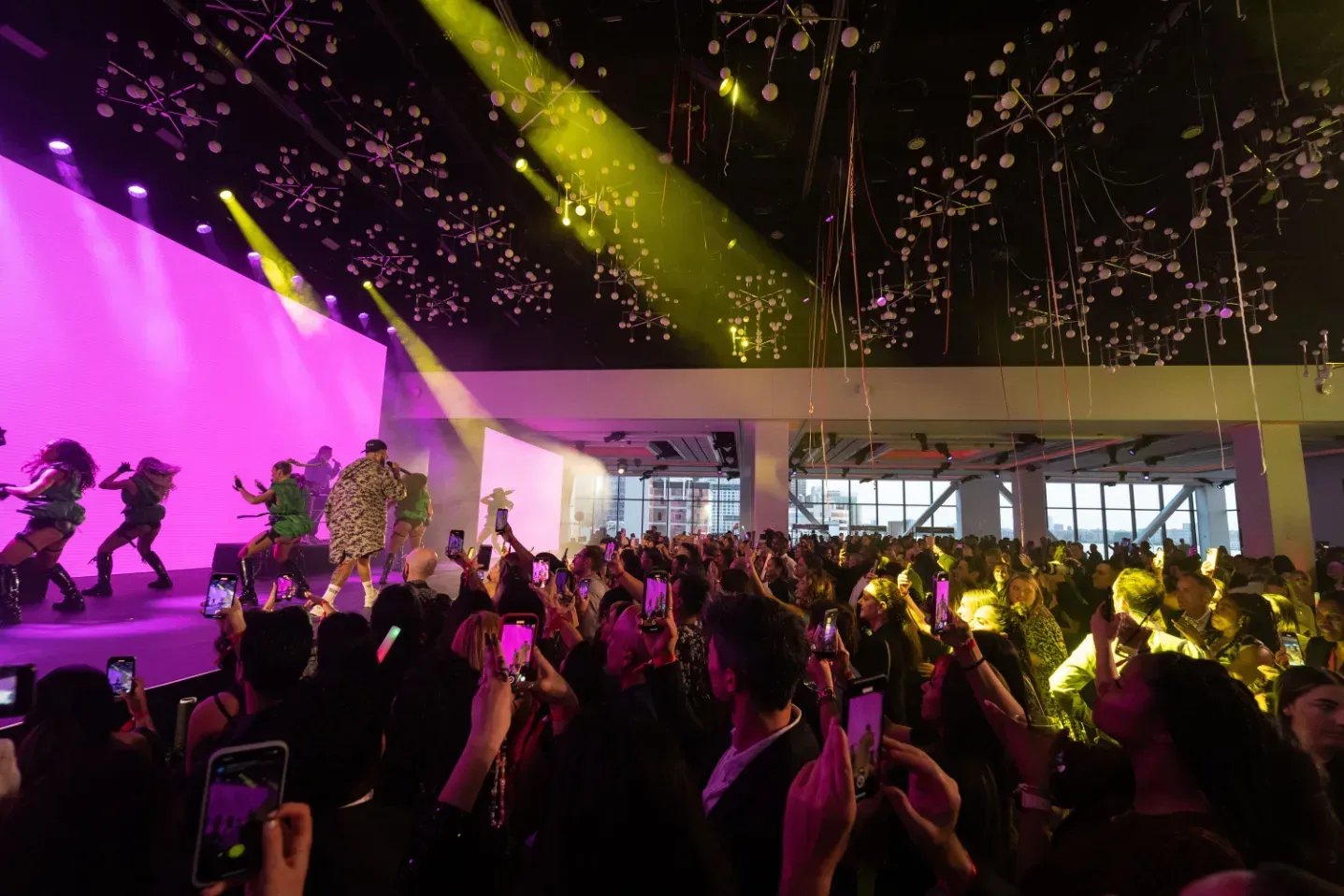 A crowd of people are standing in front of a stage at a concert.