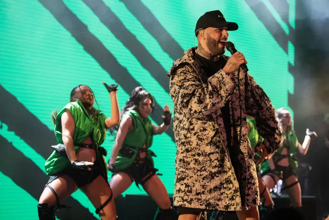 A man singing into a microphone in front of a group of dancers