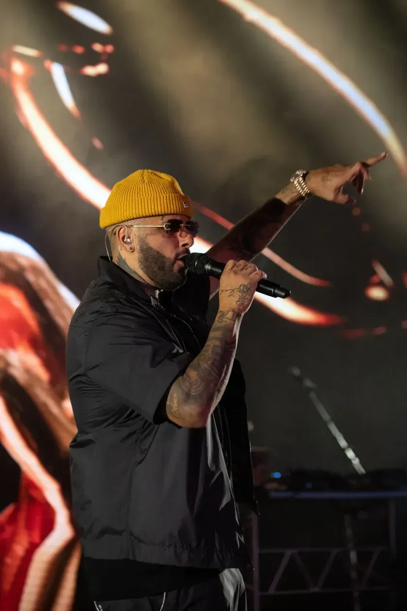 A man wearing a yellow hat is singing into a microphone on a stage.