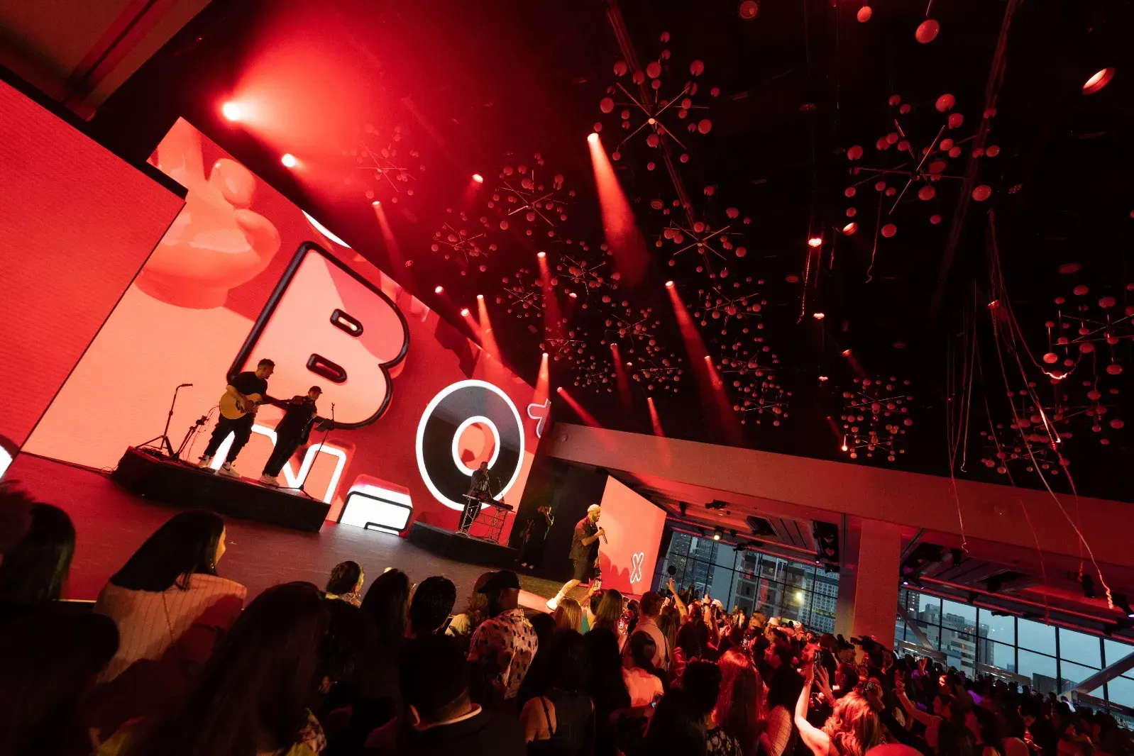 A crowd of people are watching a concert in a large room.
