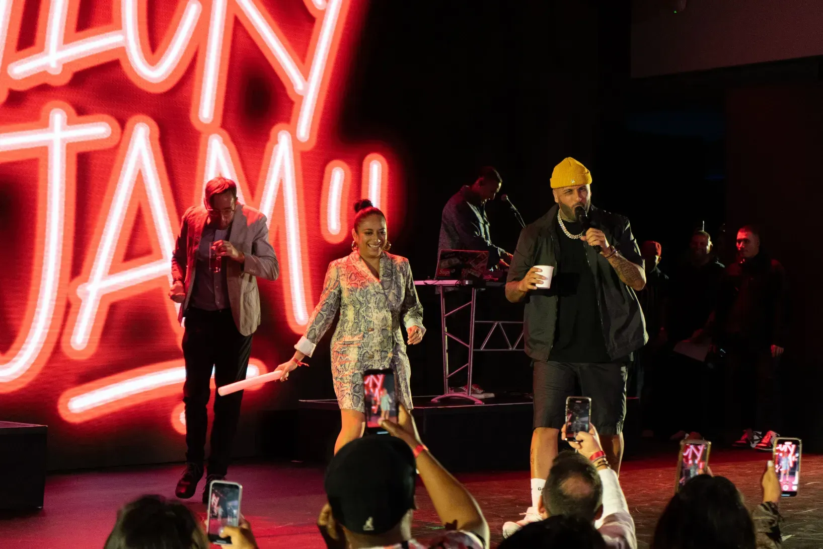 A group of people are standing on a stage in front of a neon sign.