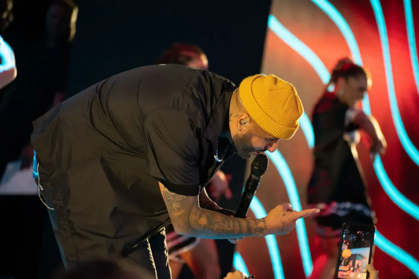 A man in a yellow hat is taking a picture of himself on a cell phone.