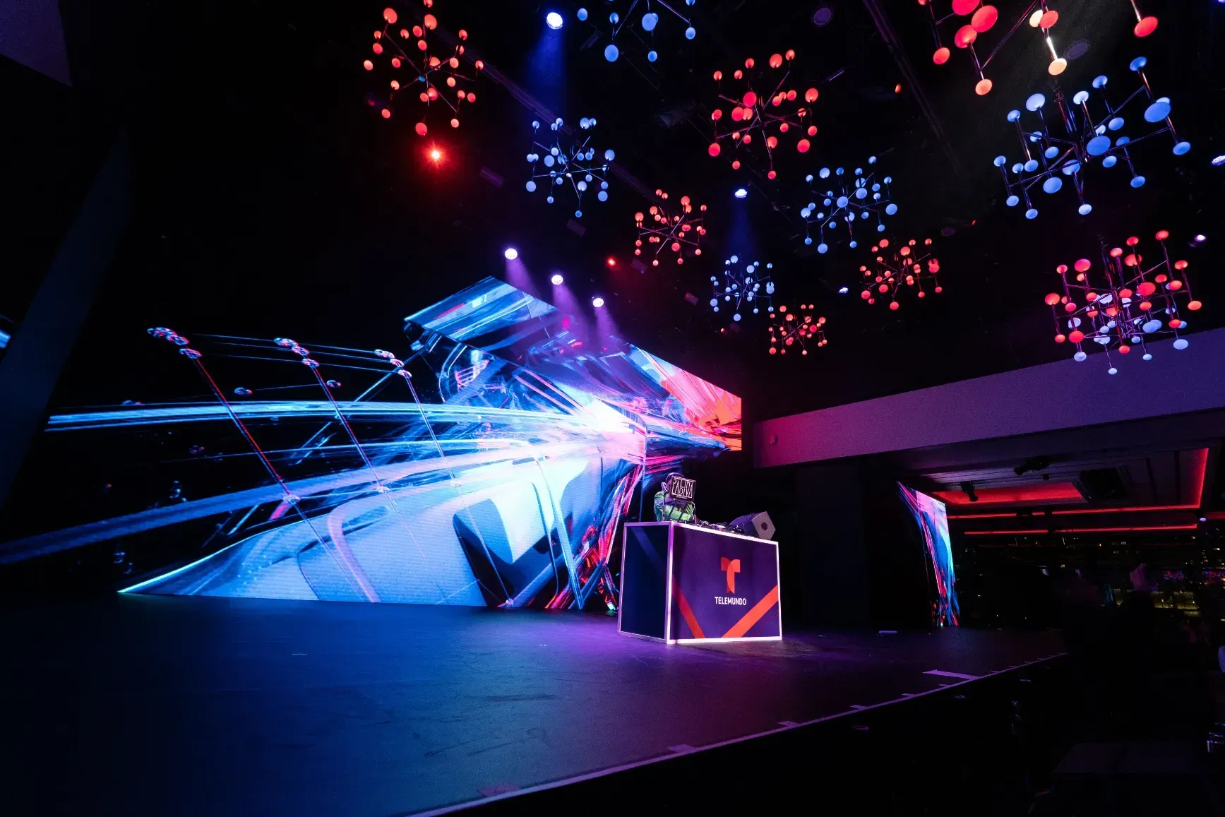 A dj is playing music on a stage in a dark room.