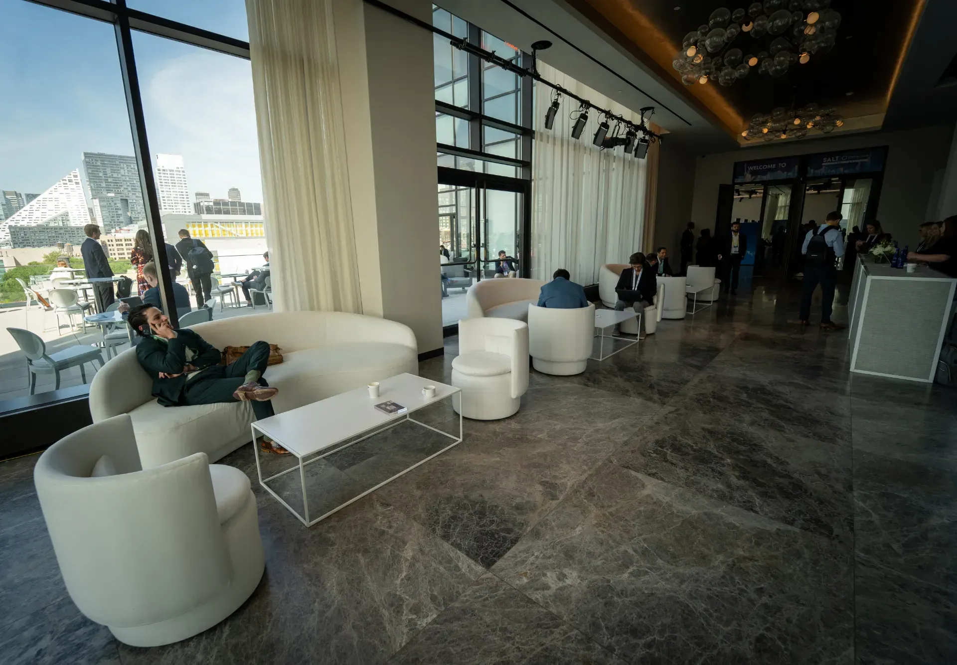 A woman is sitting on a white couch in a lobby