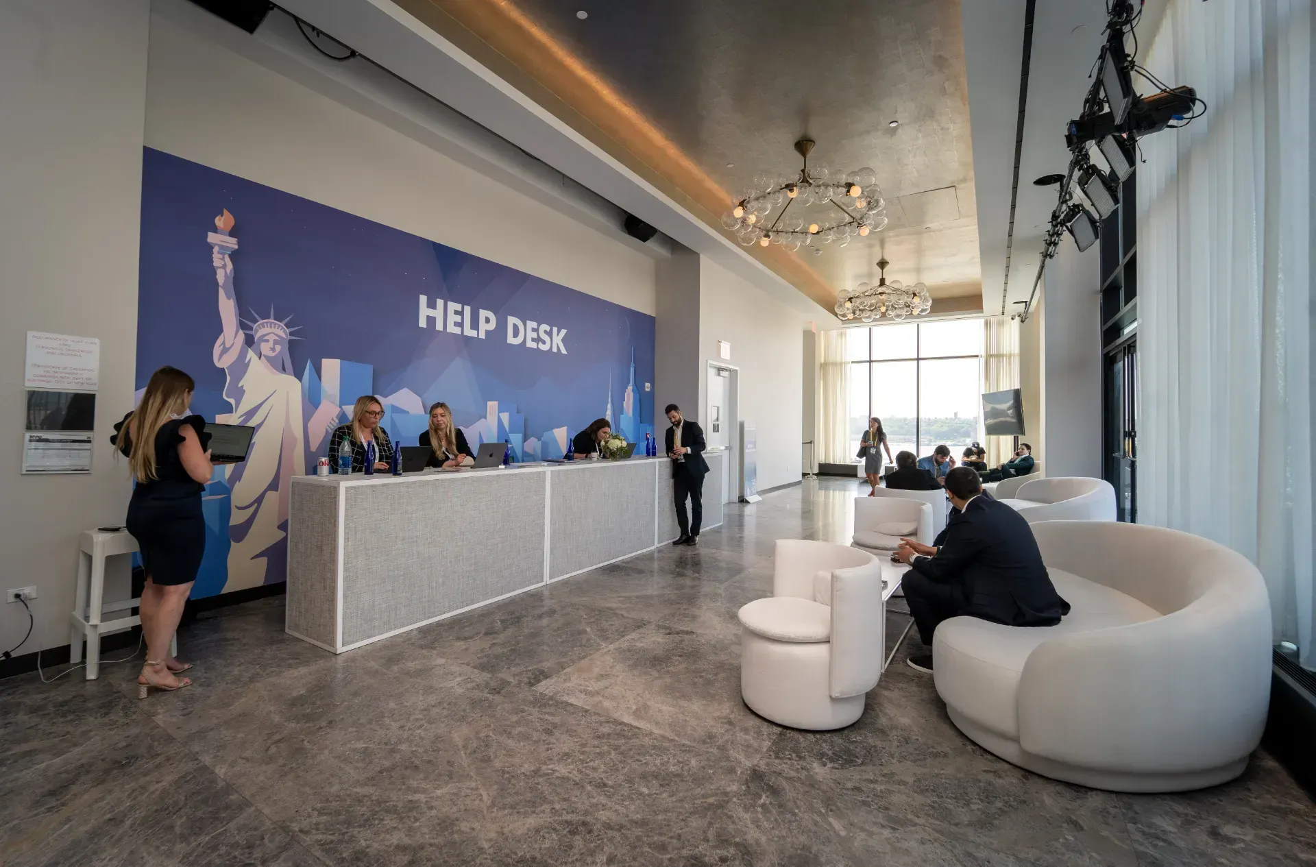 A group of people are standing at a help desk in a lobby.
