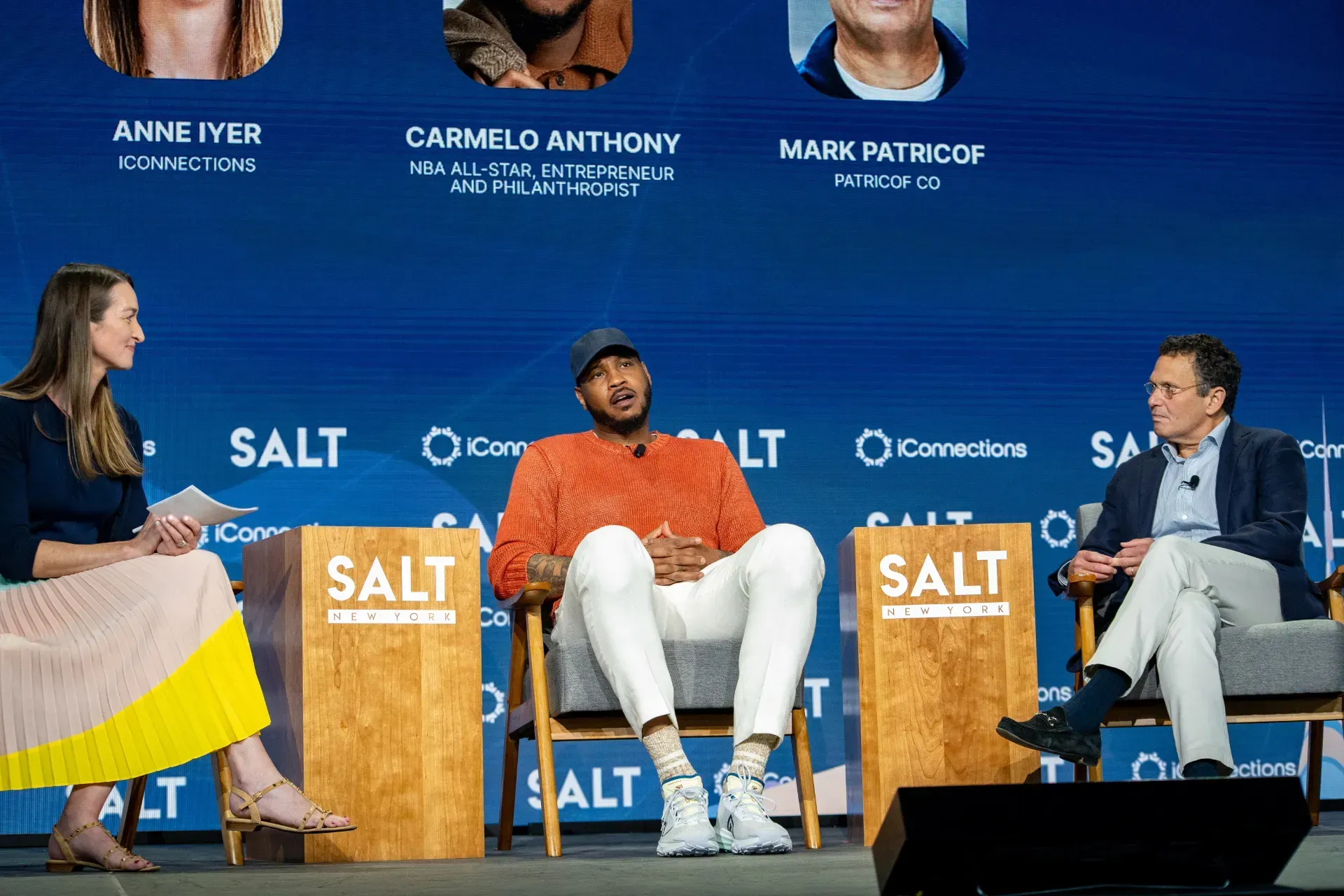 A group of people are sitting in chairs on a stage talking to each other.