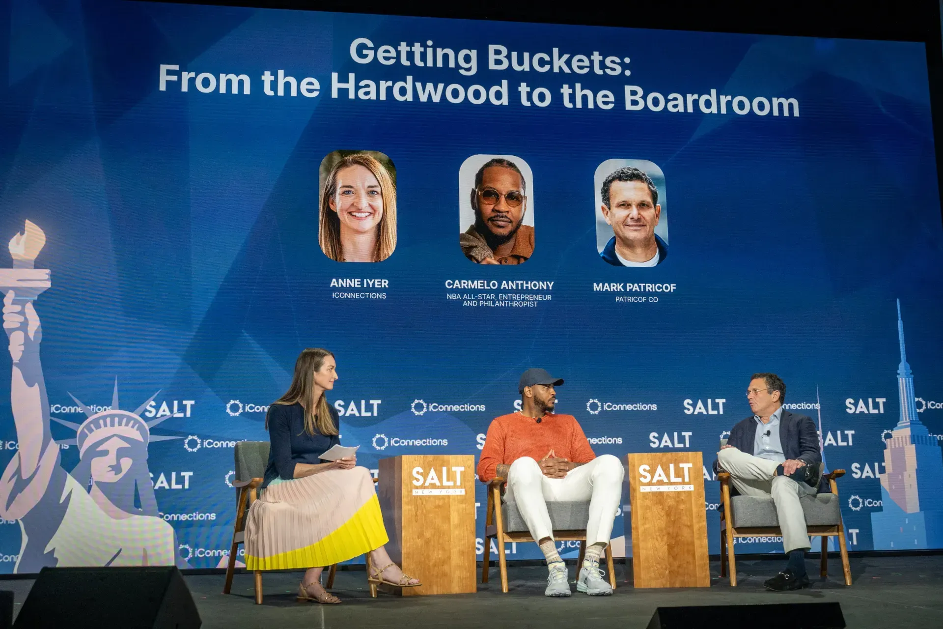 A group of people are sitting on a stage talking about getting buckets from the hardwood to the boardroom.