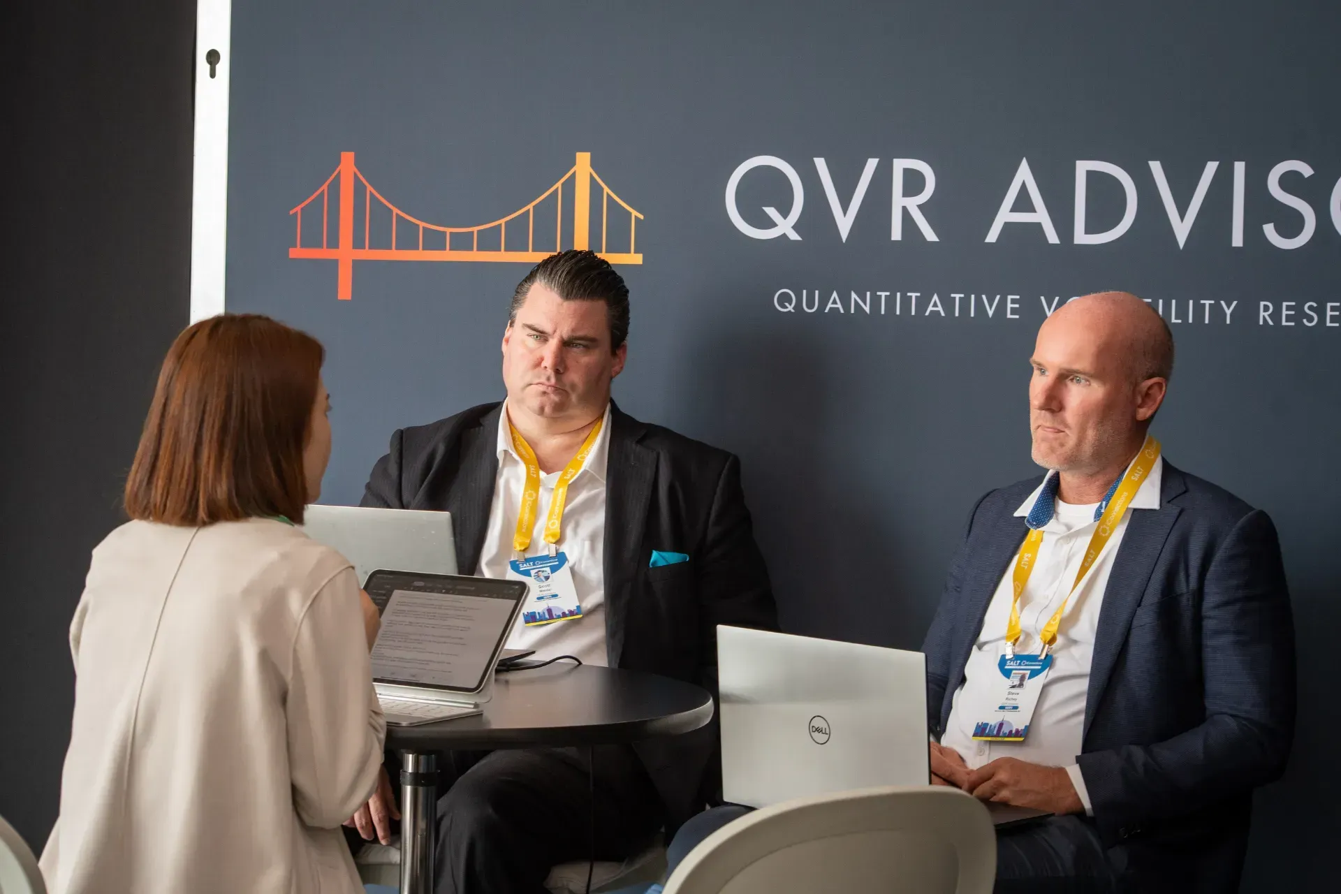 A group of people are sitting at a table with laptops.