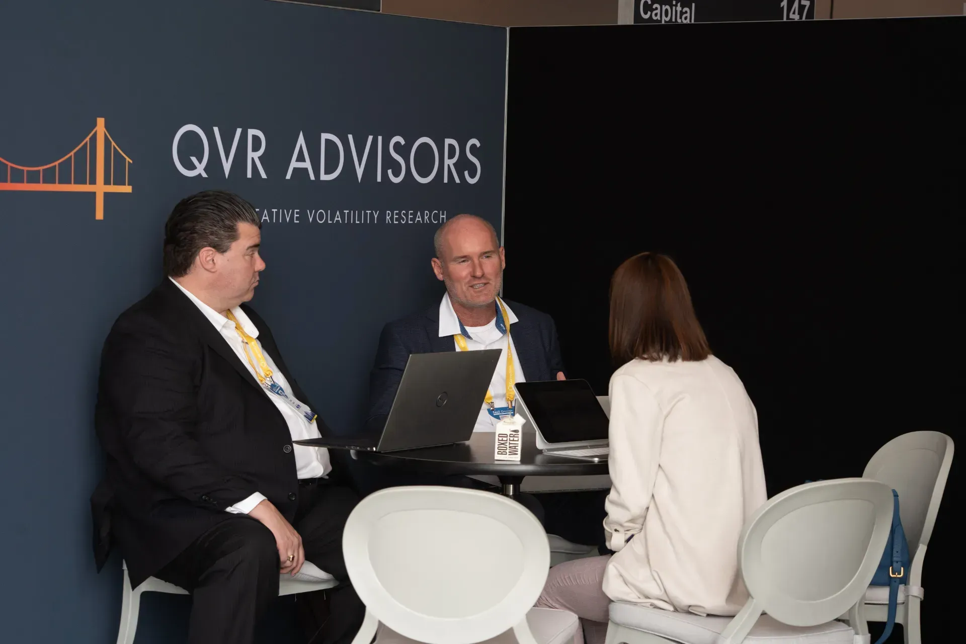 A group of people are sitting at a table in front of a sign that says qvr advisors.