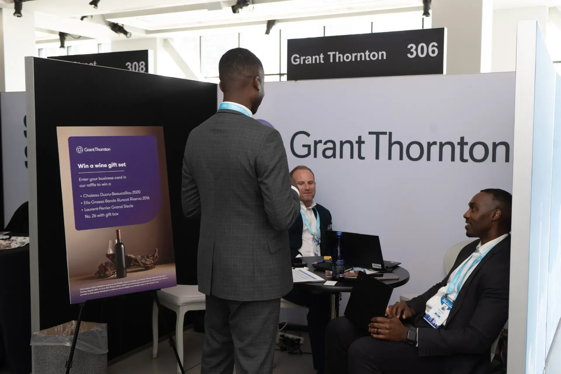 A group of men are sitting at a table in front of a sign that says grant thornton.