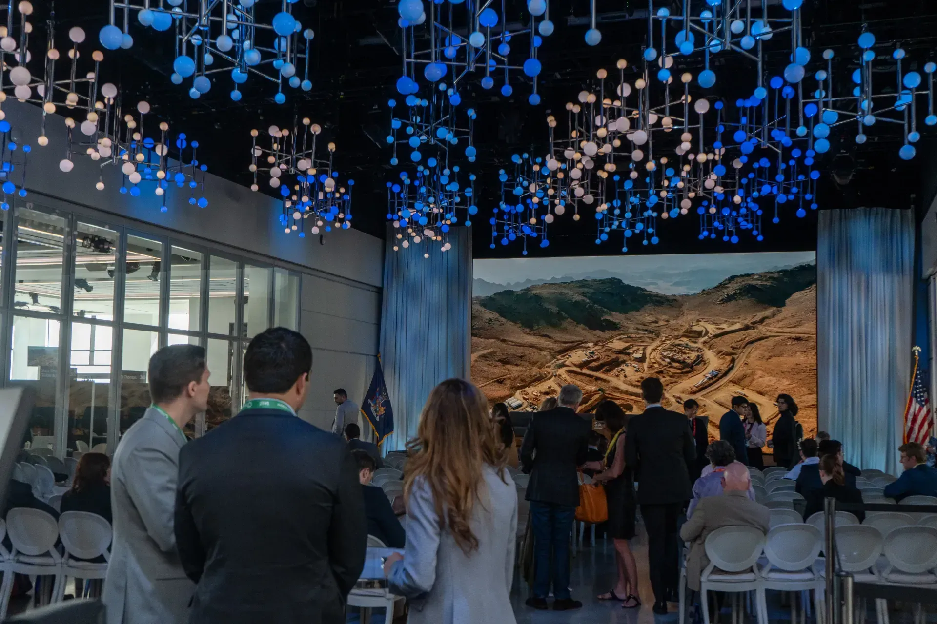 A group of people are standing in a room in front of a large screen.