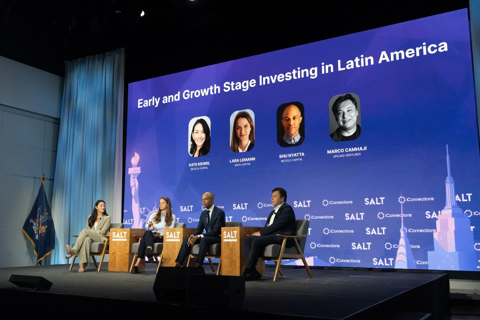 A group of people are sitting in front of a large screen that says early and growth stage investing in latin america
