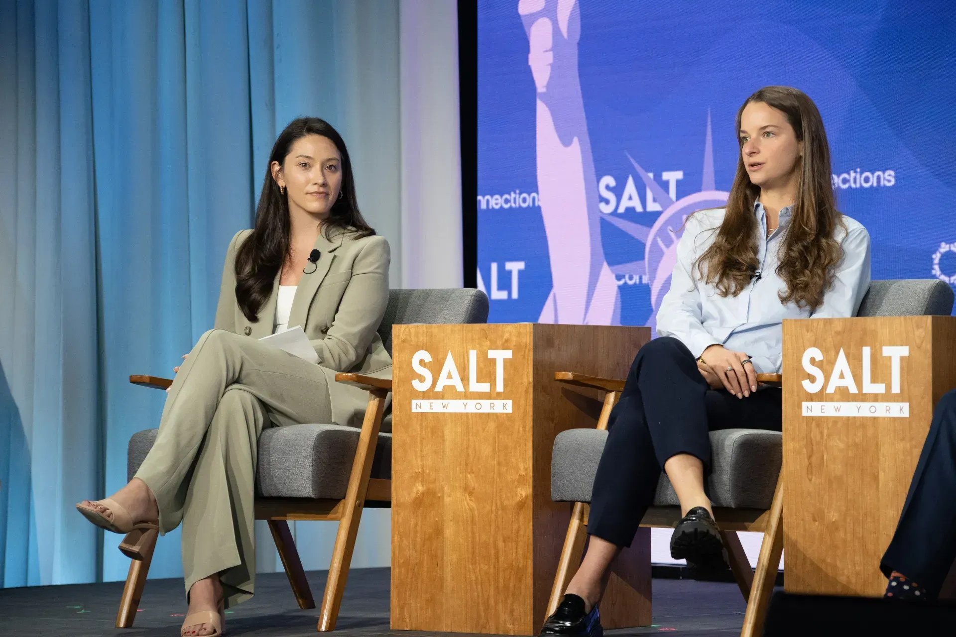 Two women are sitting in chairs on a stage.
