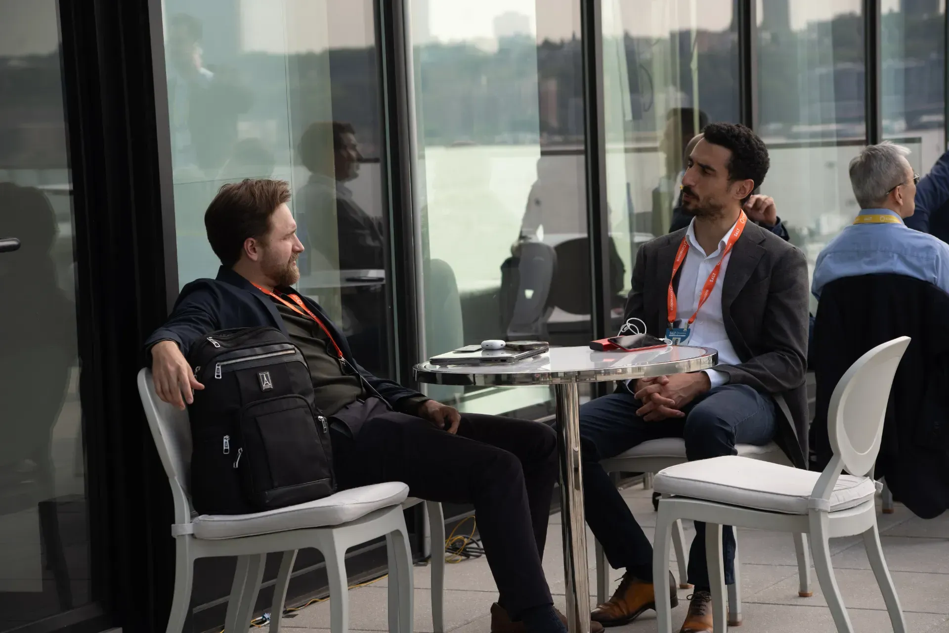 Two men are sitting at a table talking to each other.