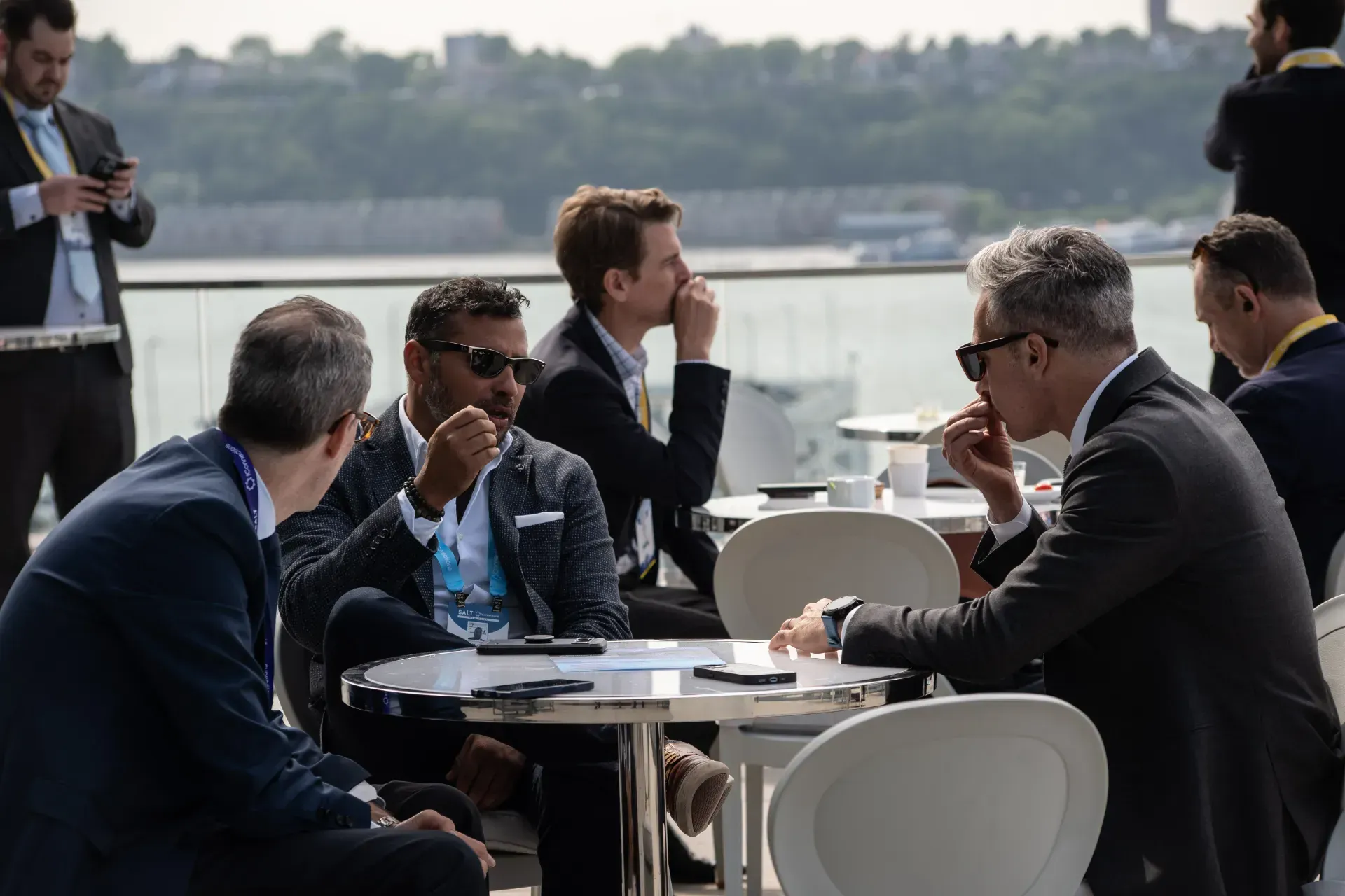 A group of men are sitting at tables talking to each other.