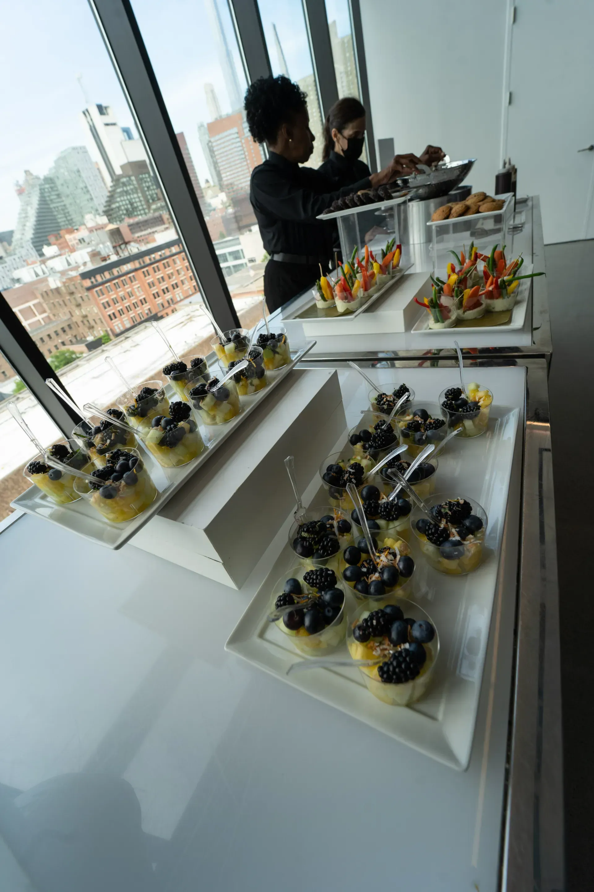 A woman is standing behind a table filled with plates of food.