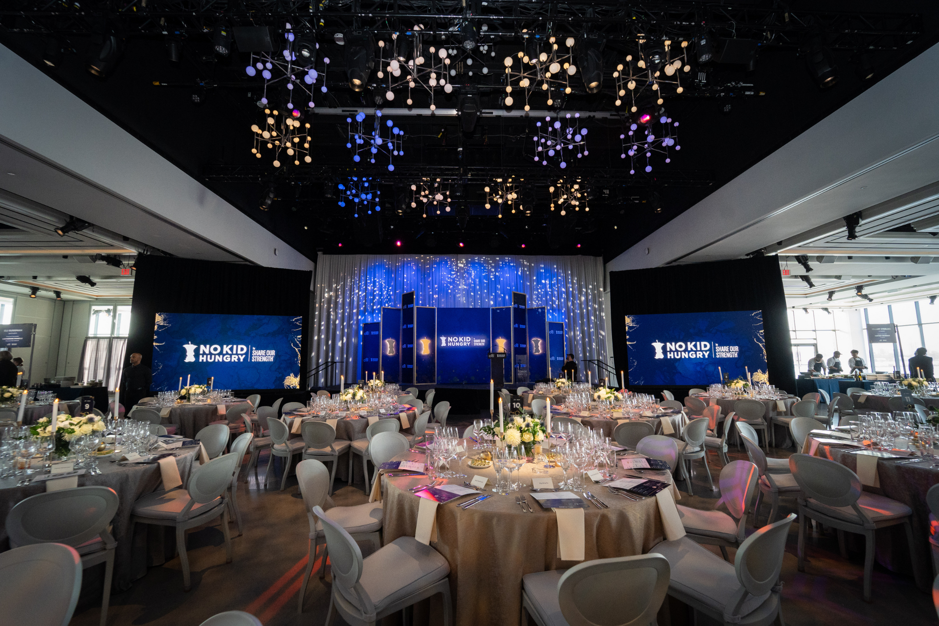 A large room filled with tables and chairs and a stage.