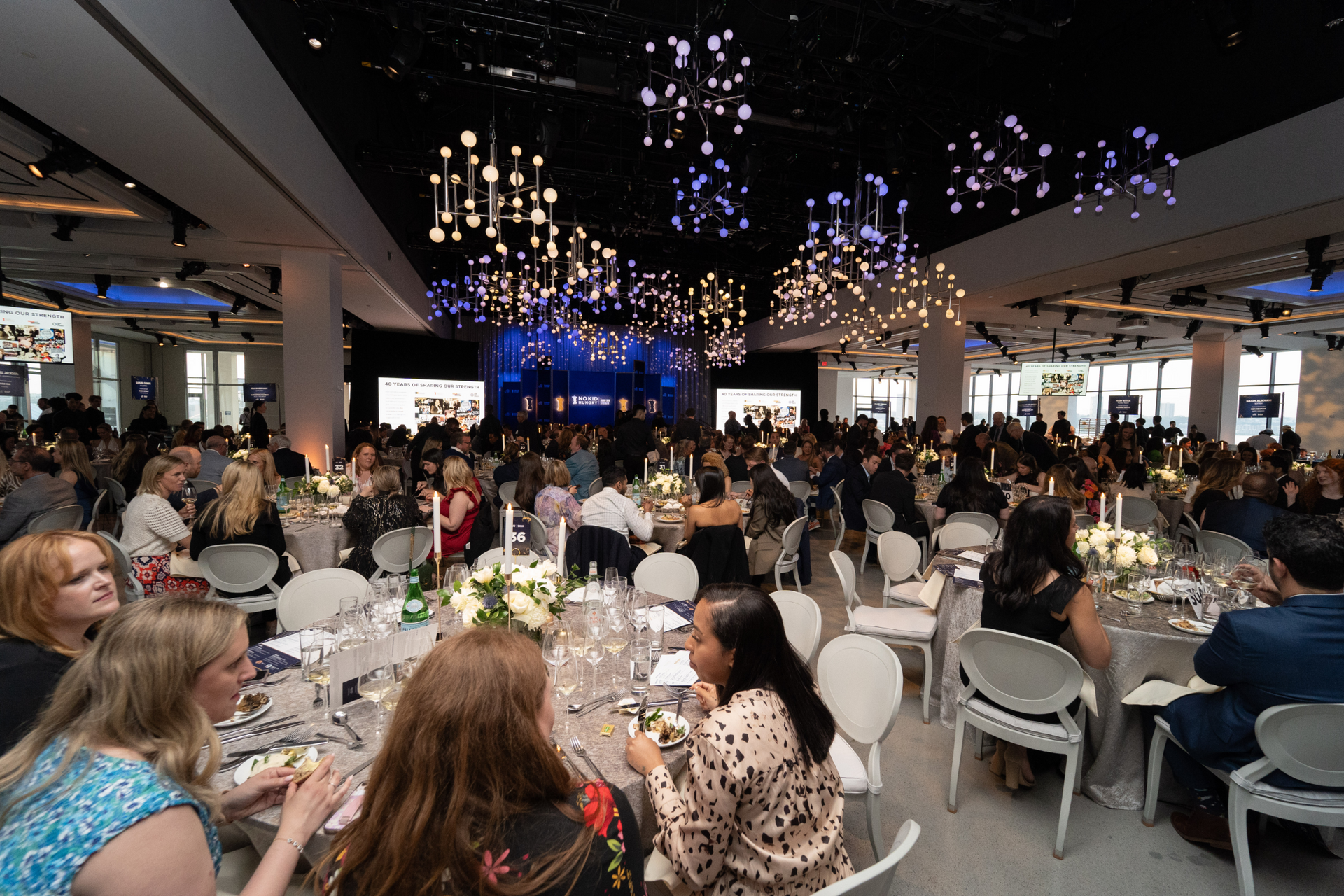 A large room filled with people sitting at tables and chairs.