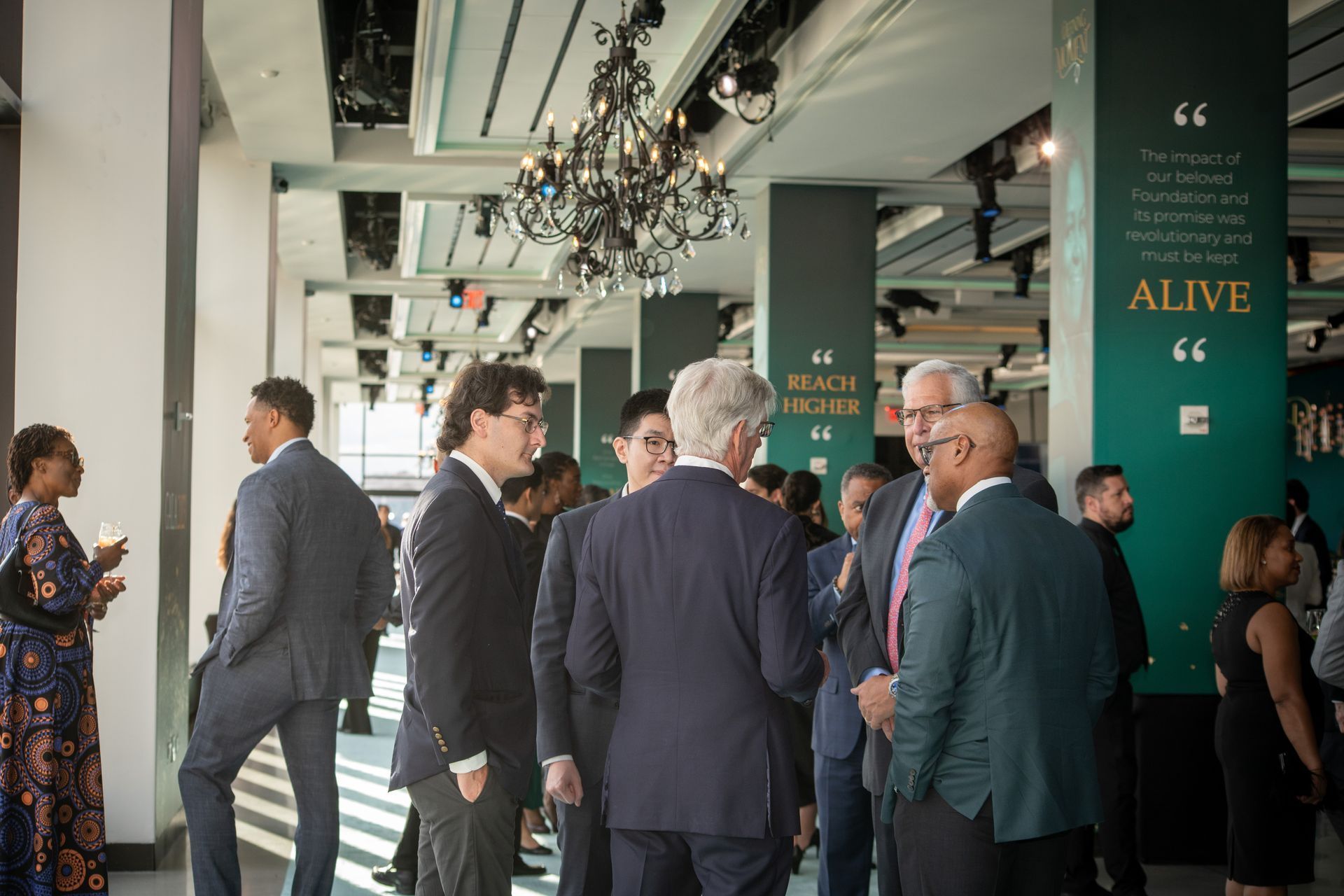 A group of people in suits are standing in a room talking to each other.