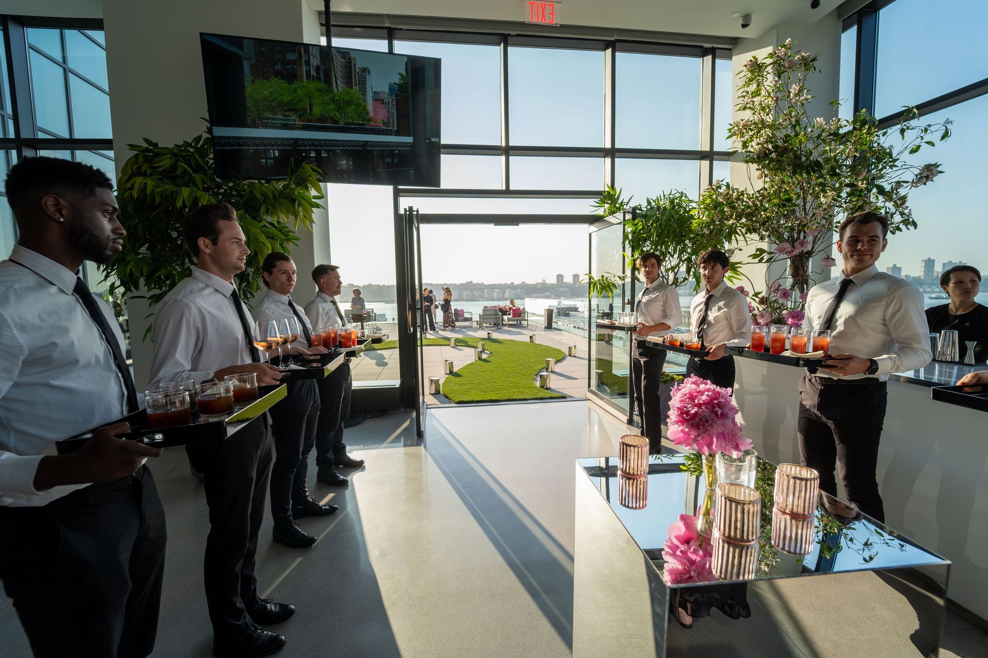 A group of men are standing in a room holding trays of drinks.